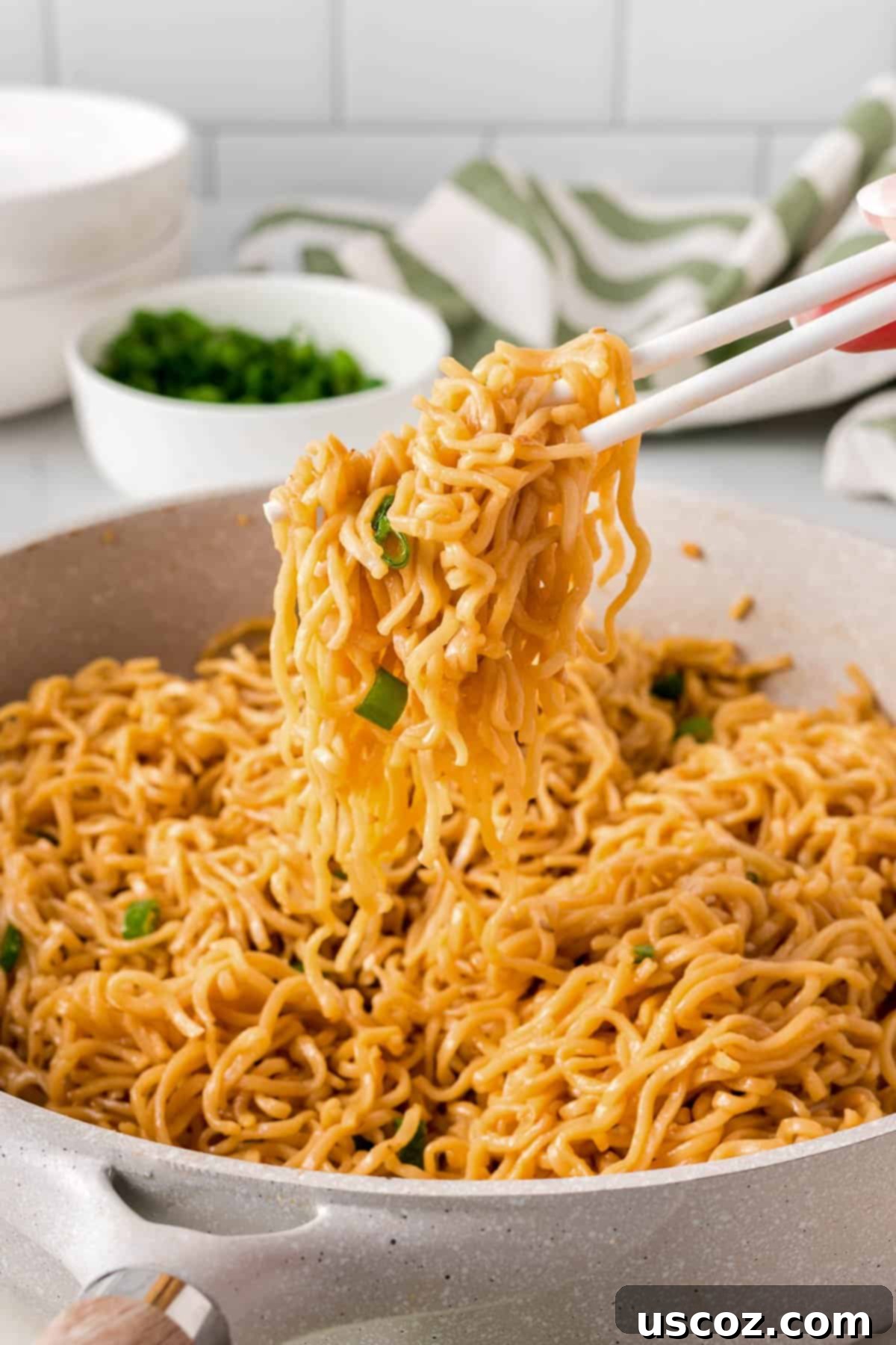 Easy Sesame Garlic Ramen 13 Chopsticks lifting a perfect mouthful of sesame garlic ramen noodles from a rustic skillet, highlighting the saucy texture and readiness to eat.