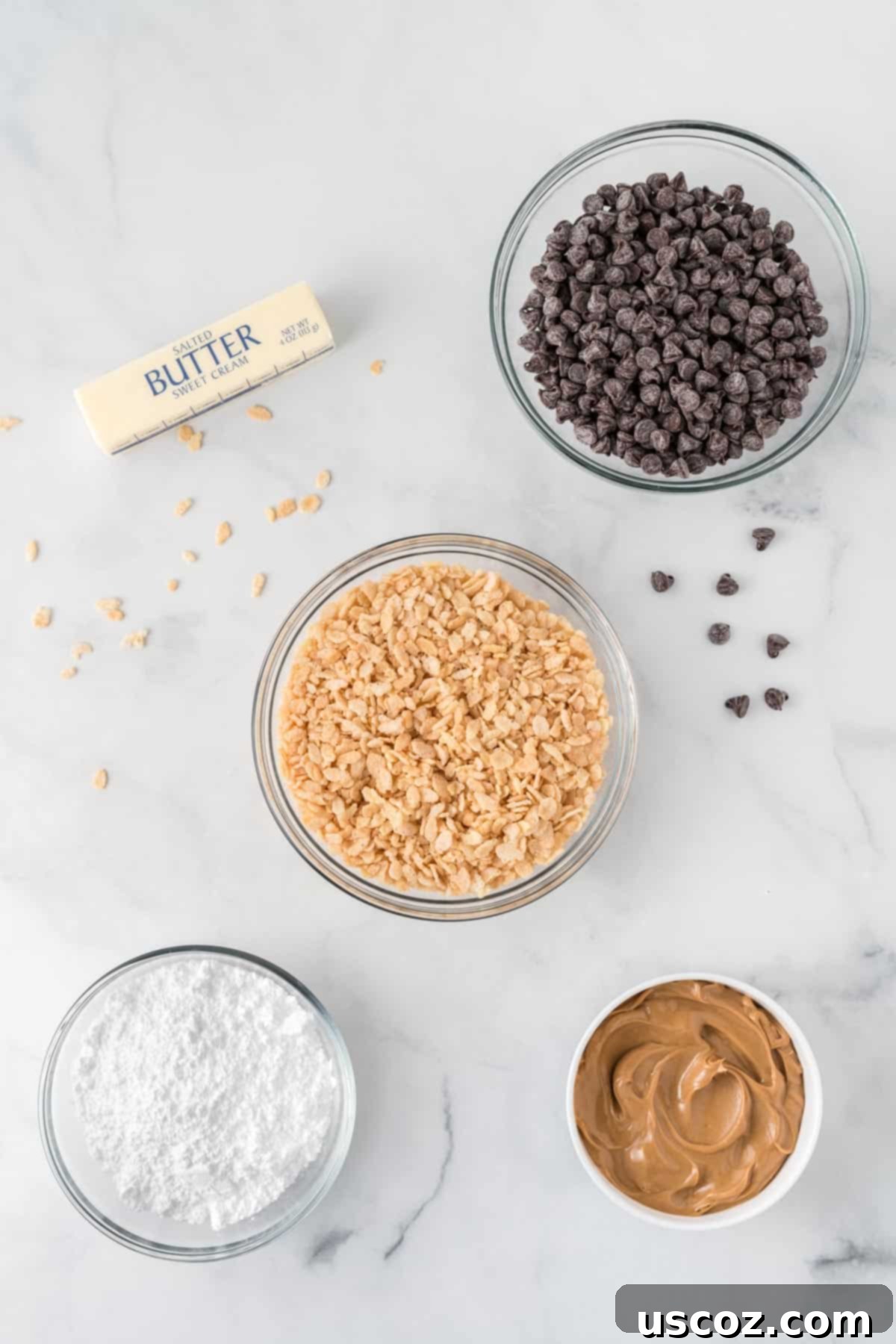 No-Bake Peanut Butter Krispie Treats 4 Close-up of ingredients needed: melted butter, creamy peanut butter, Rice Krispies cereal, powdered sugar, and semi-sweet chocolate chips, all laid out for making peanut butter balls.