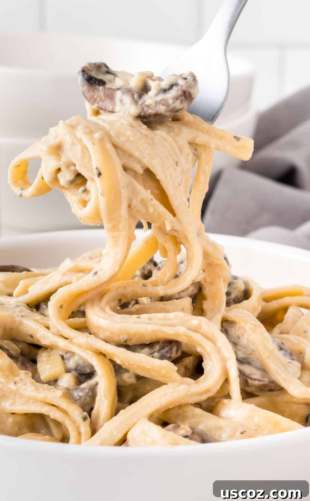Velvety Mushroom Pasta 12 A fork twirling a generous portion of creamy mushroom pasta from a bowl, highlighting the luscious sauce.
