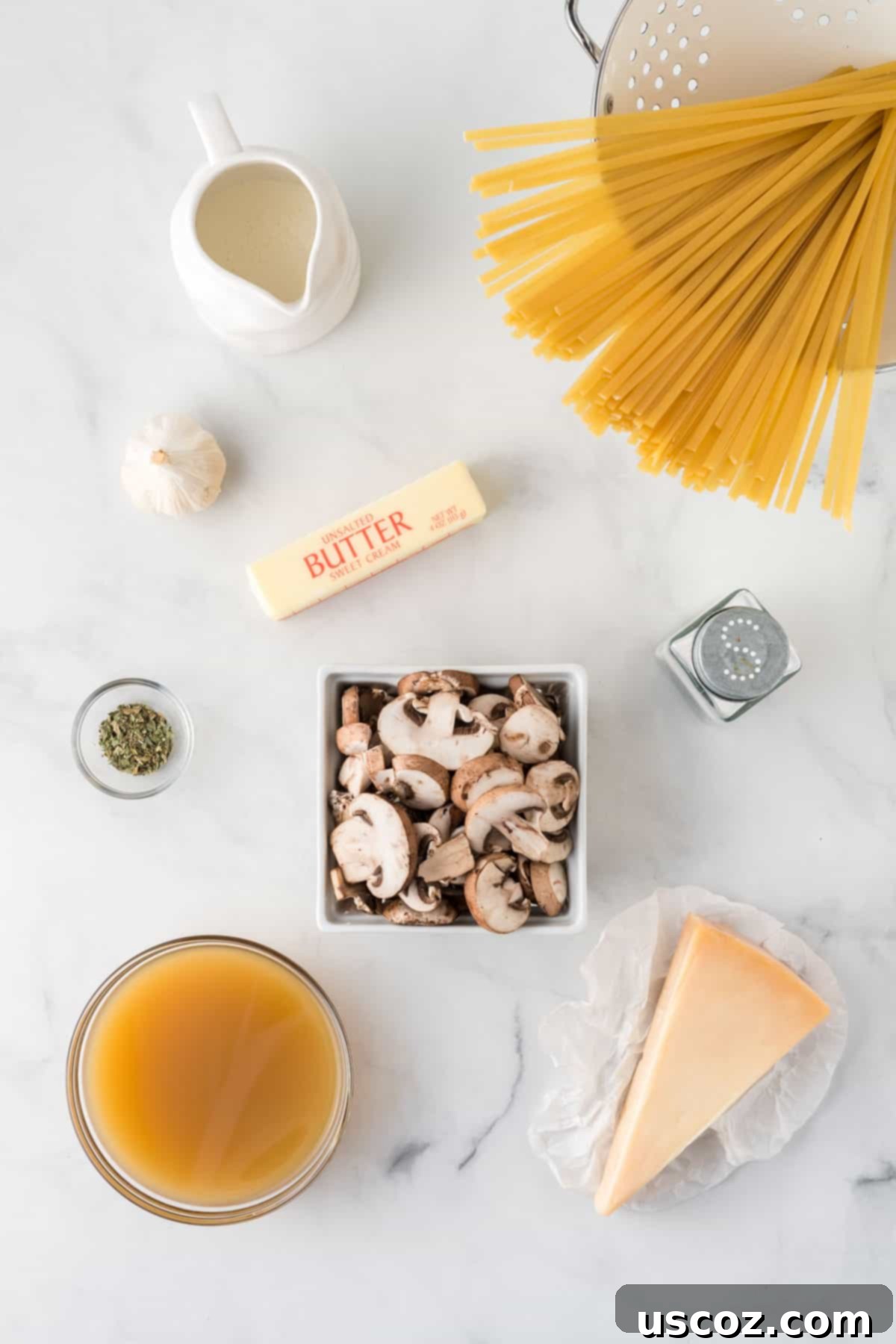 Velvety Mushroom Pasta 4 A collection of fresh ingredients laid out on a wooden board, including baby bella mushrooms, fresh garlic, fettuccine, heavy cream, and parmesan cheese, ready for creamy mushroom pasta preparation.