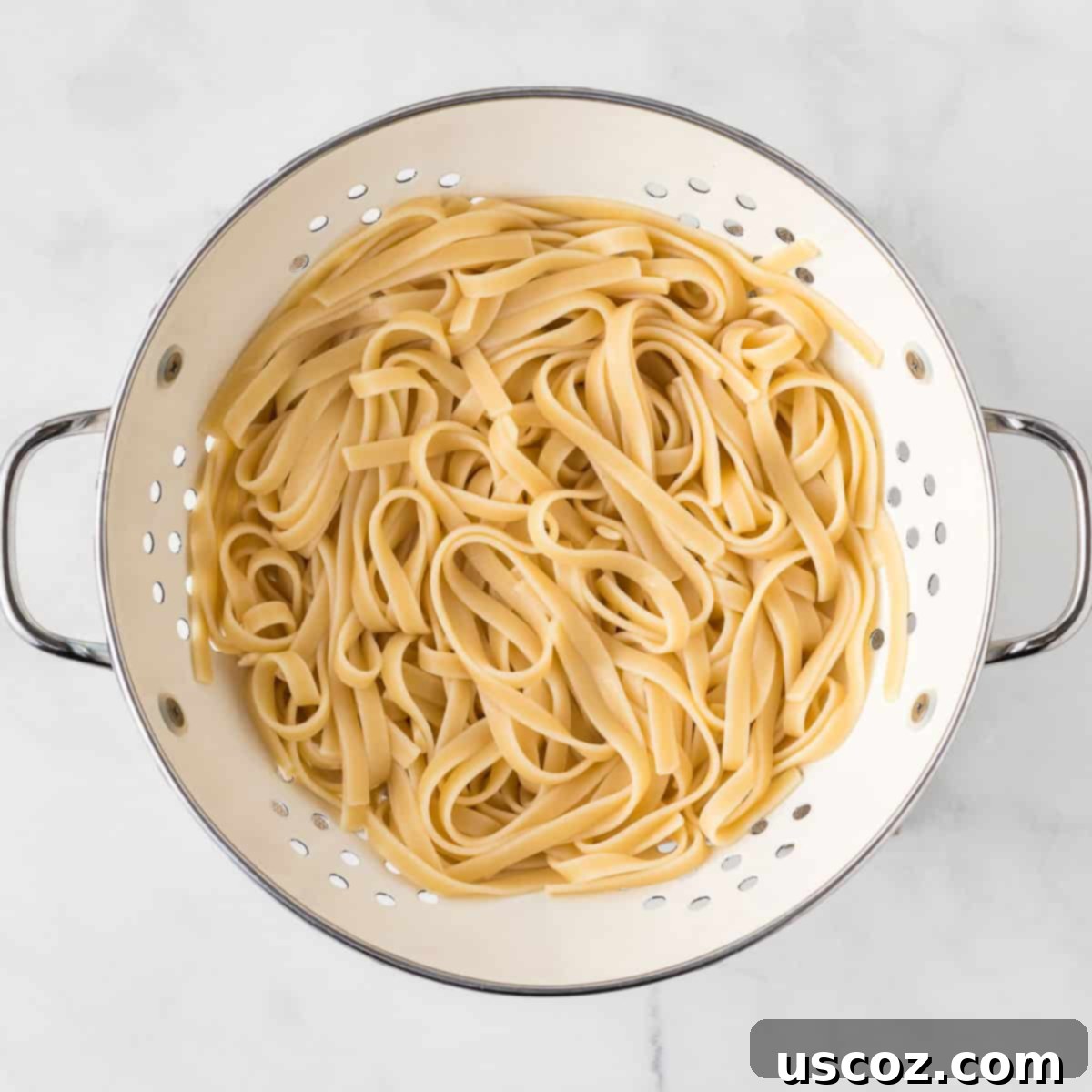Velvety Mushroom Pasta 7 Freshly cooked fettuccine pasta in a colander, having just been drained from its cooking water.