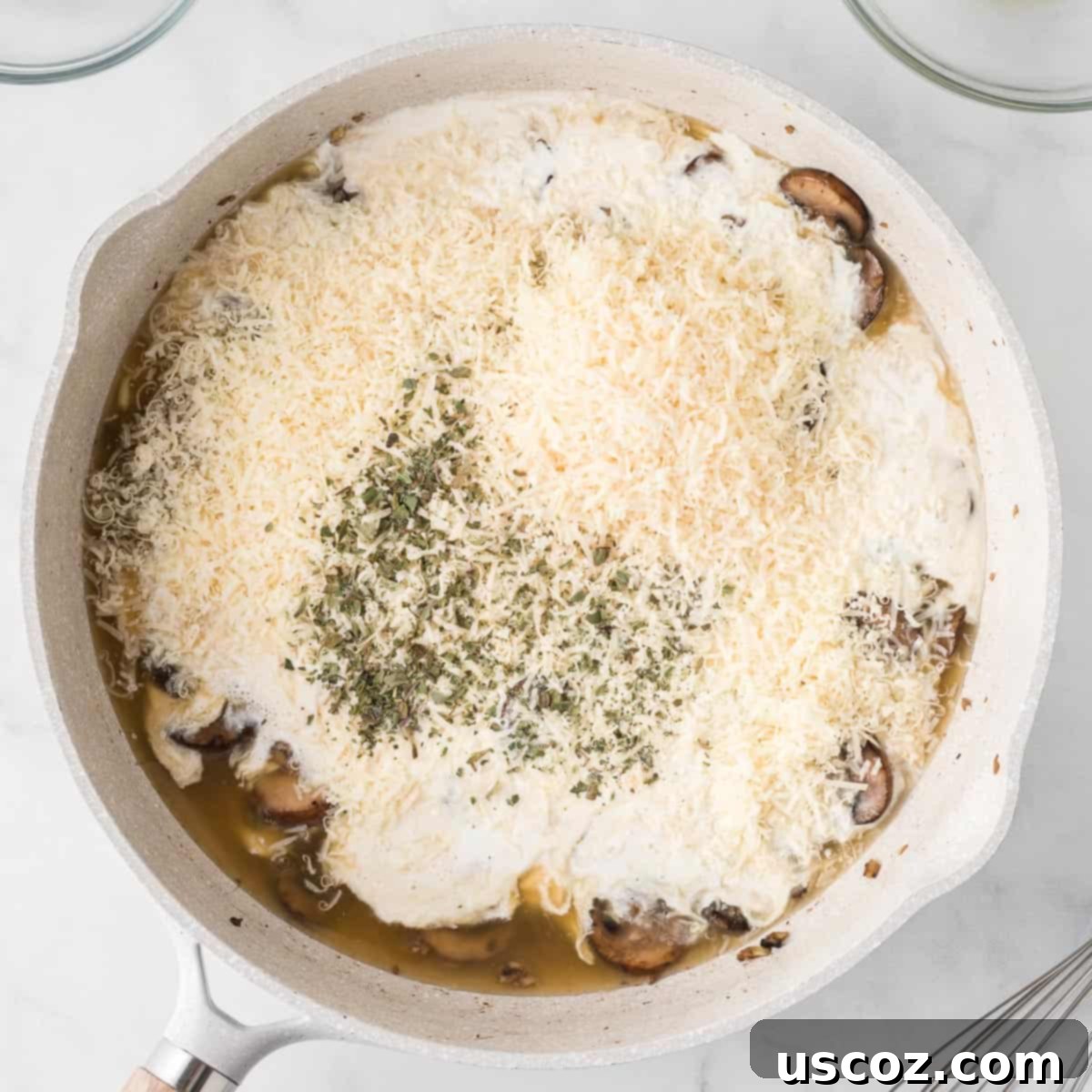 Velvety Mushroom Pasta 8 Heavy cream, parmesan cheese, and oregano being added to the cooked mushrooms and garlic in a skillet to form the creamy sauce.