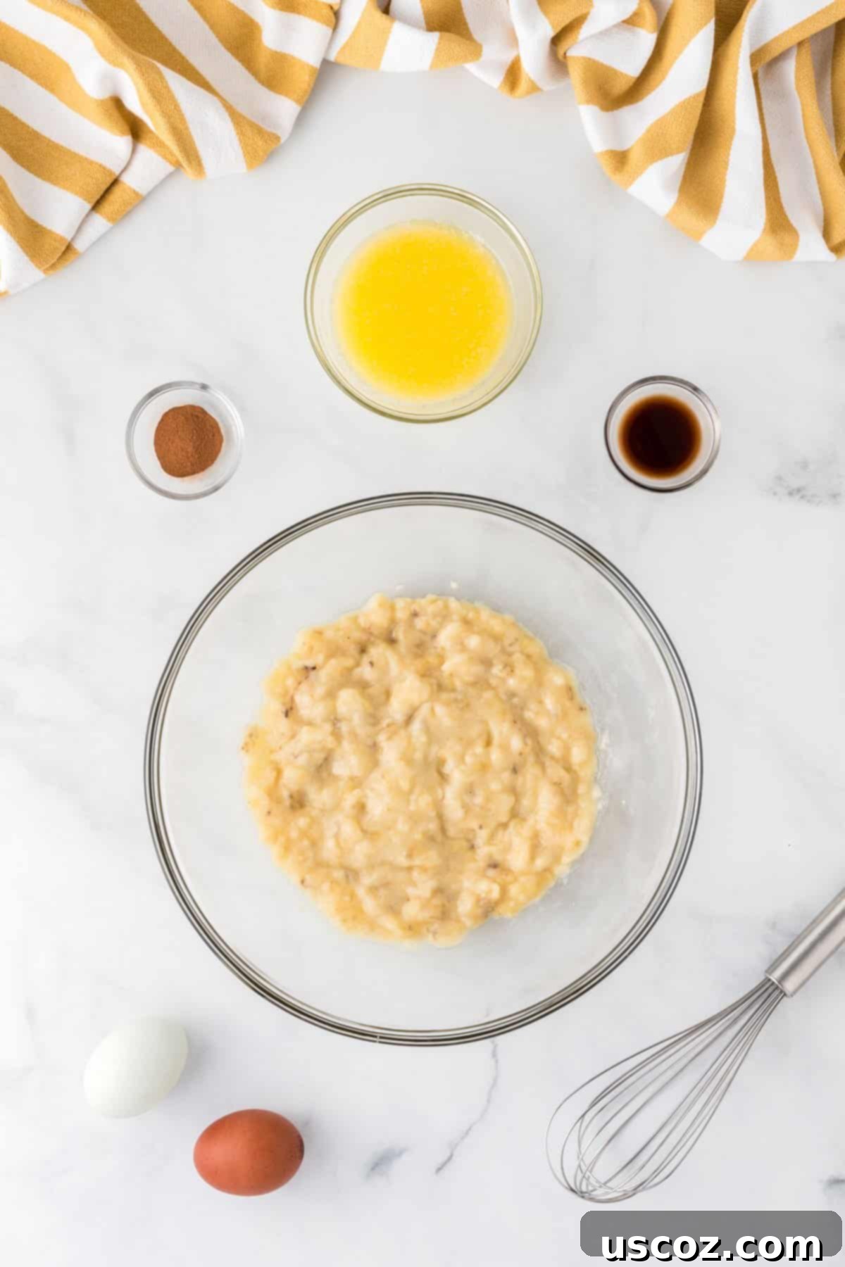 Easy Cake Mix Banana Muffins 5 Bowl containing mashed overripe bananas, two raw eggs, melted butter, vanilla extract, and cinnamon, ready to be whisked together for banana muffin batter.