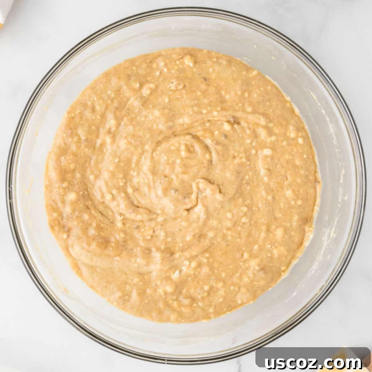 Easy Cake Mix Banana Muffins 8 Close-up of fully mixed cake mix banana muffin batter in a white bowl, showing its thick and slightly lumpy consistency.