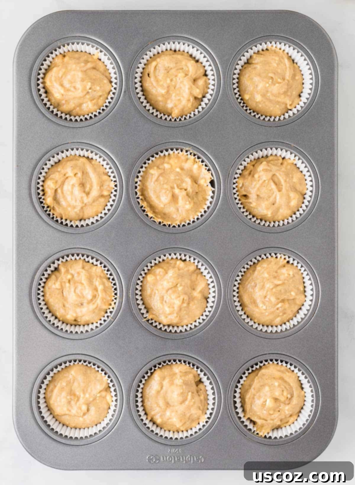 Easy Cake Mix Banana Muffins 9 Muffin tin lined with paper cups, filled evenly with cake mix banana muffin batter, ready for baking.