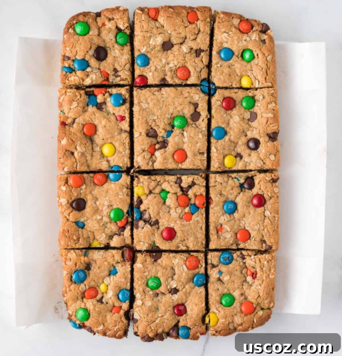 Everything-But-The-Kitchen-Sink Cookie Bars 12 Perfectly cut Monster Cookie Bars arranged on a plate, showcasing their inviting texture and colorful M&M's, ready to be enjoyed.