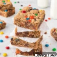 Everything-But-The-Kitchen-Sink Cookie Bars 16 monster cookie bars stacked between pieces of parchment paper