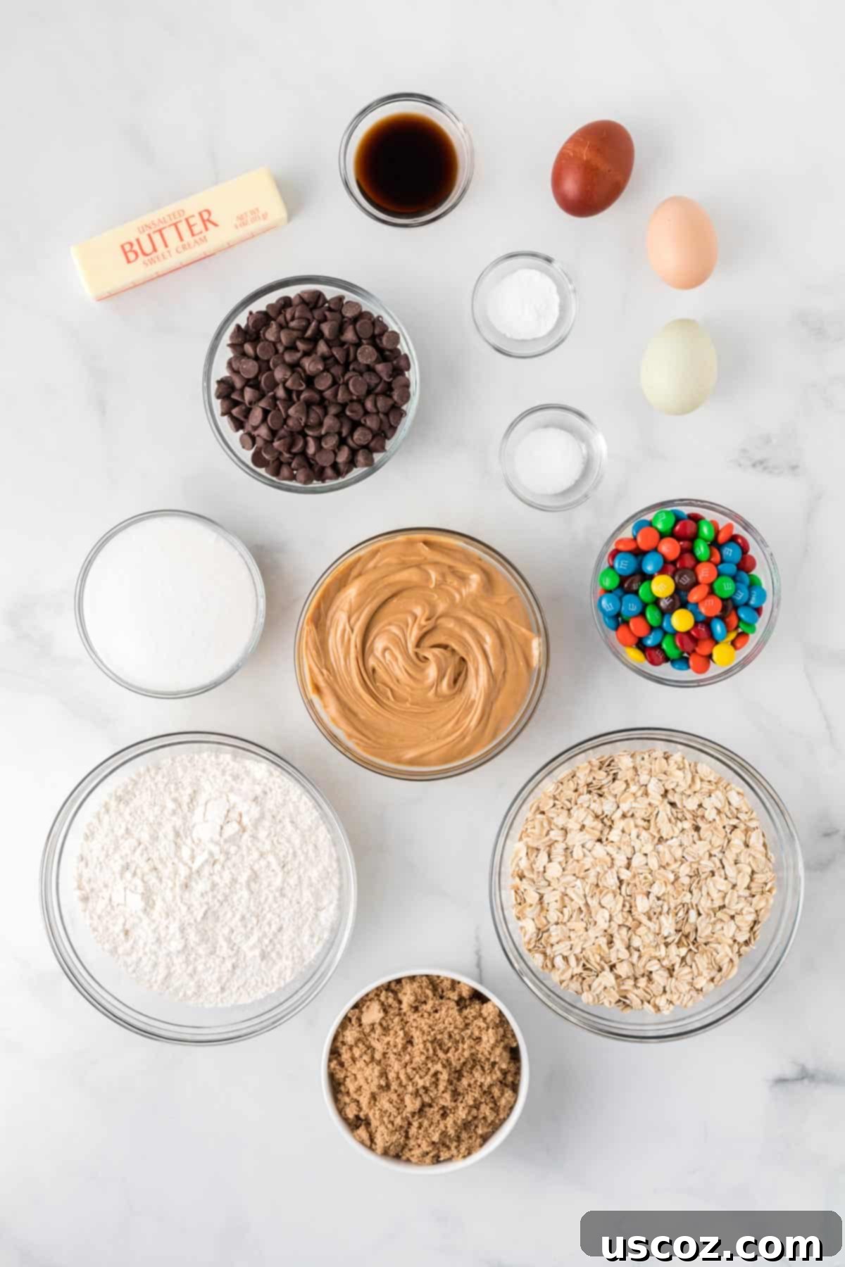 Everything-But-The-Kitchen-Sink Cookie Bars 4 Assortment of dry and wet ingredients laid out neatly, including oats, flour, sugars, peanut butter, M&M's, and chocolate chips, ready for making monster cookie bars.