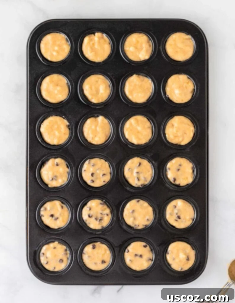 Bite-Sized Banana Muffins 10 A mini muffin tin filled with half plain banana muffin batter and half banana chocolate chip muffin batter