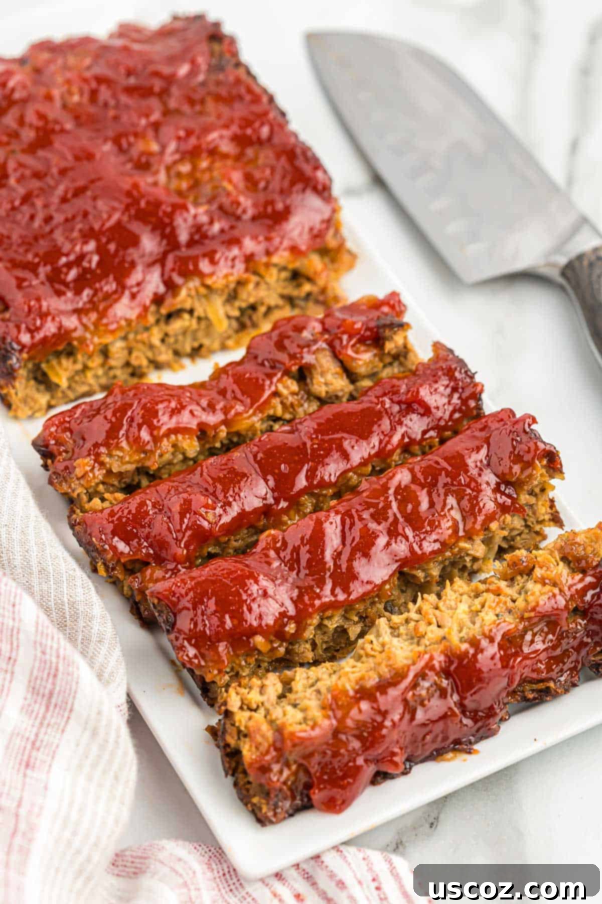 Hearty Plant-Based Meatloaf 16 Close-up of a generous, perfectly browned slice of vegetarian meatloaf on a white plate