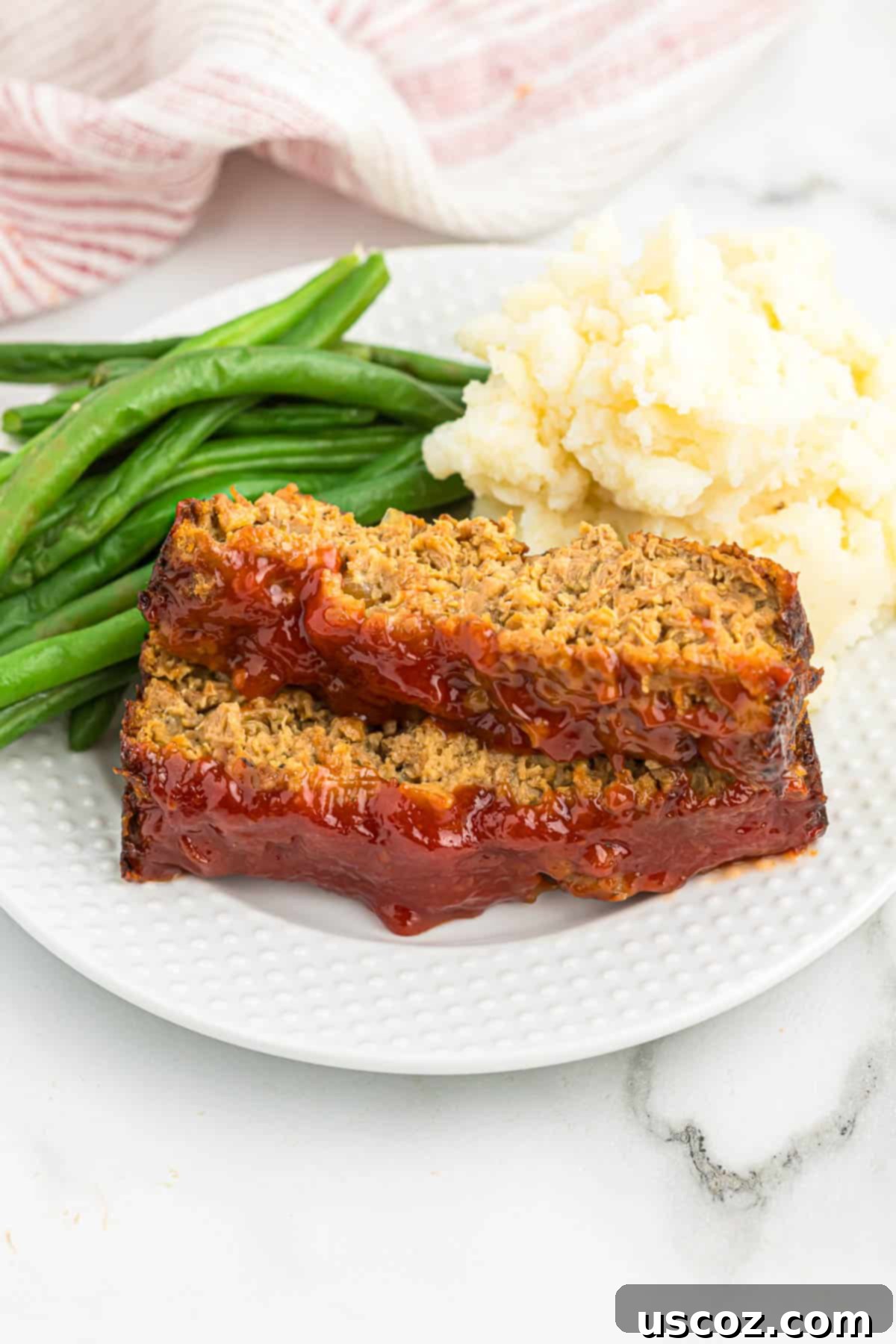 Hearty Plant-Based Meatloaf 3 Close-up of a tender slice of vegetarian meatloaf alongside vibrant green beans and creamy mashed potatoes