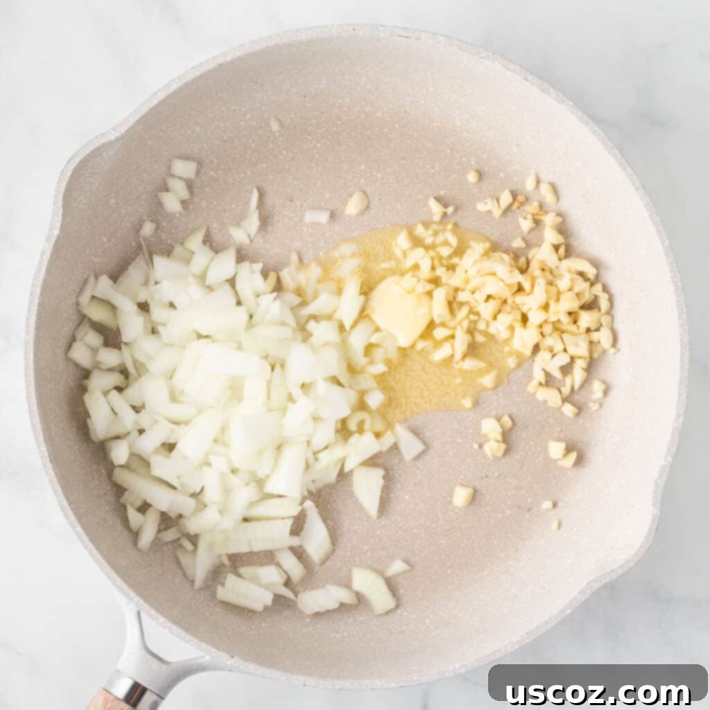 Hearty Plant-Based Meatloaf 6 Fresh garlic cloves and diced yellow onion being sautéed in a skillet with melted butter
