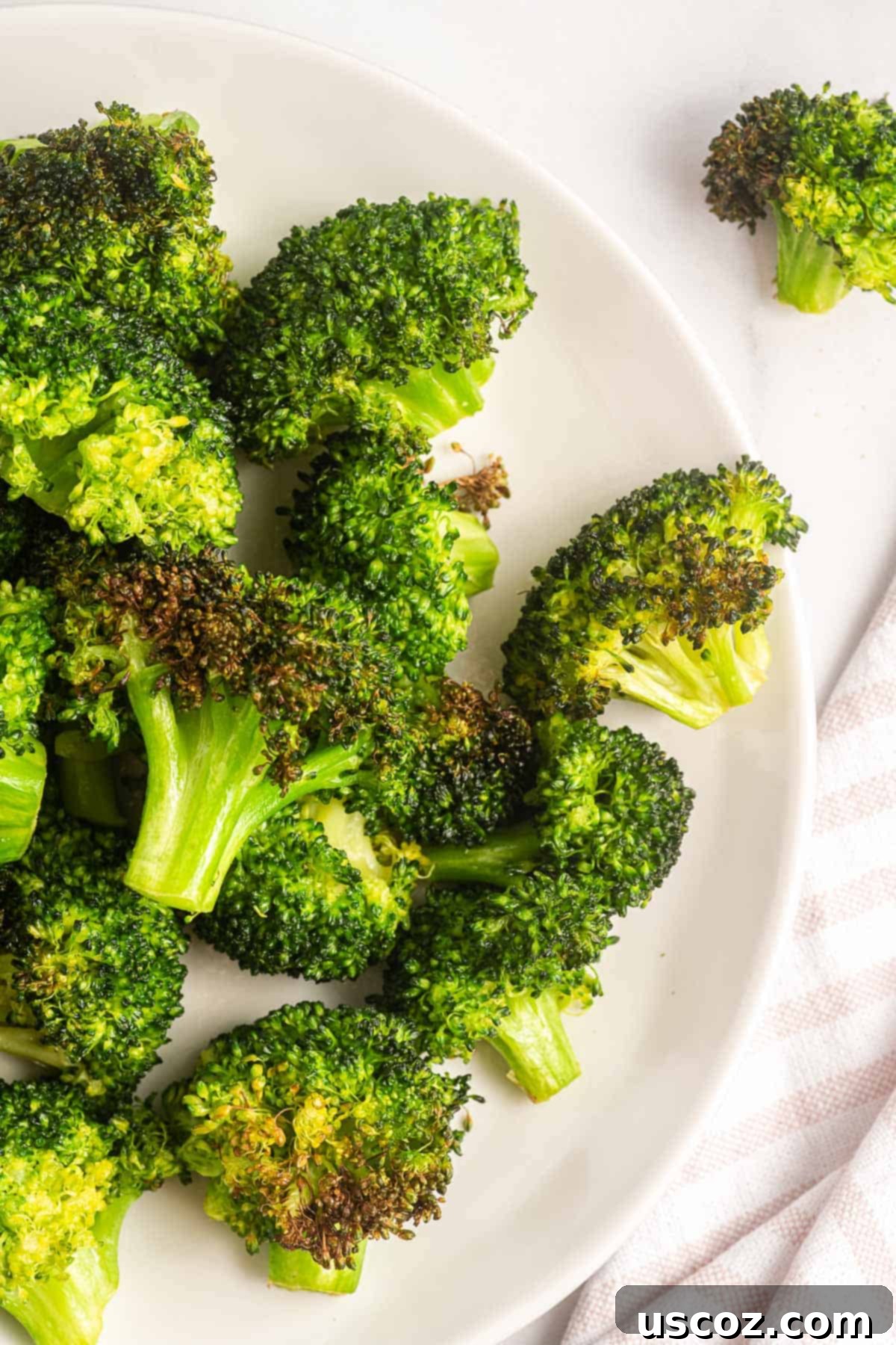 Perfectly Crispy Air Fryer Broccoli 6 Perfectly air fried broccoli florets served on a clean white plate, ready to enjoy as a healthy side dish.