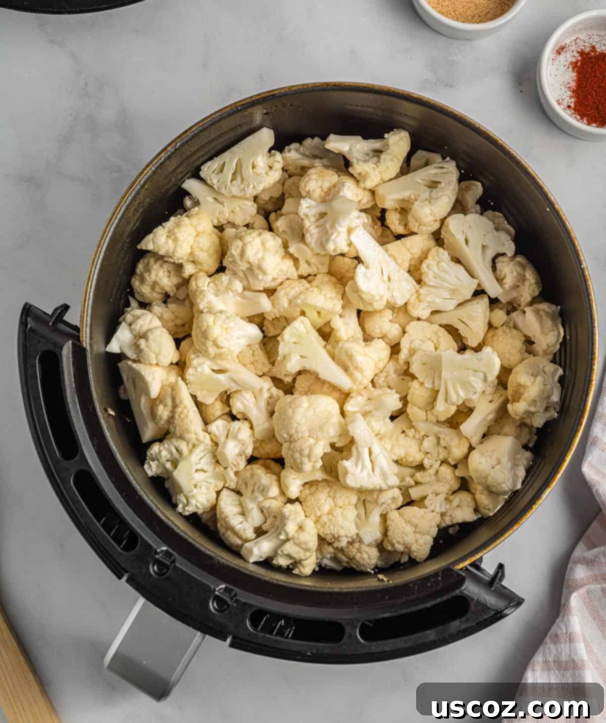 Crispy Air Fryer Cauliflower 5 Cauliflower florets freshly sprayed with olive oil in an air fryer basket, before seasoning.