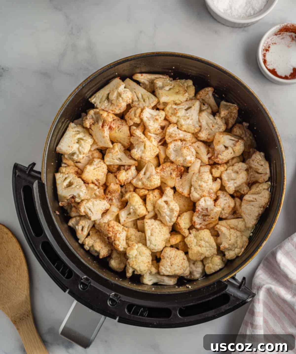 Crispy Air Fryer Cauliflower 6 Cauliflower florets in an air fryer basket, perfectly tossed and coated with a vibrant blend of spices.