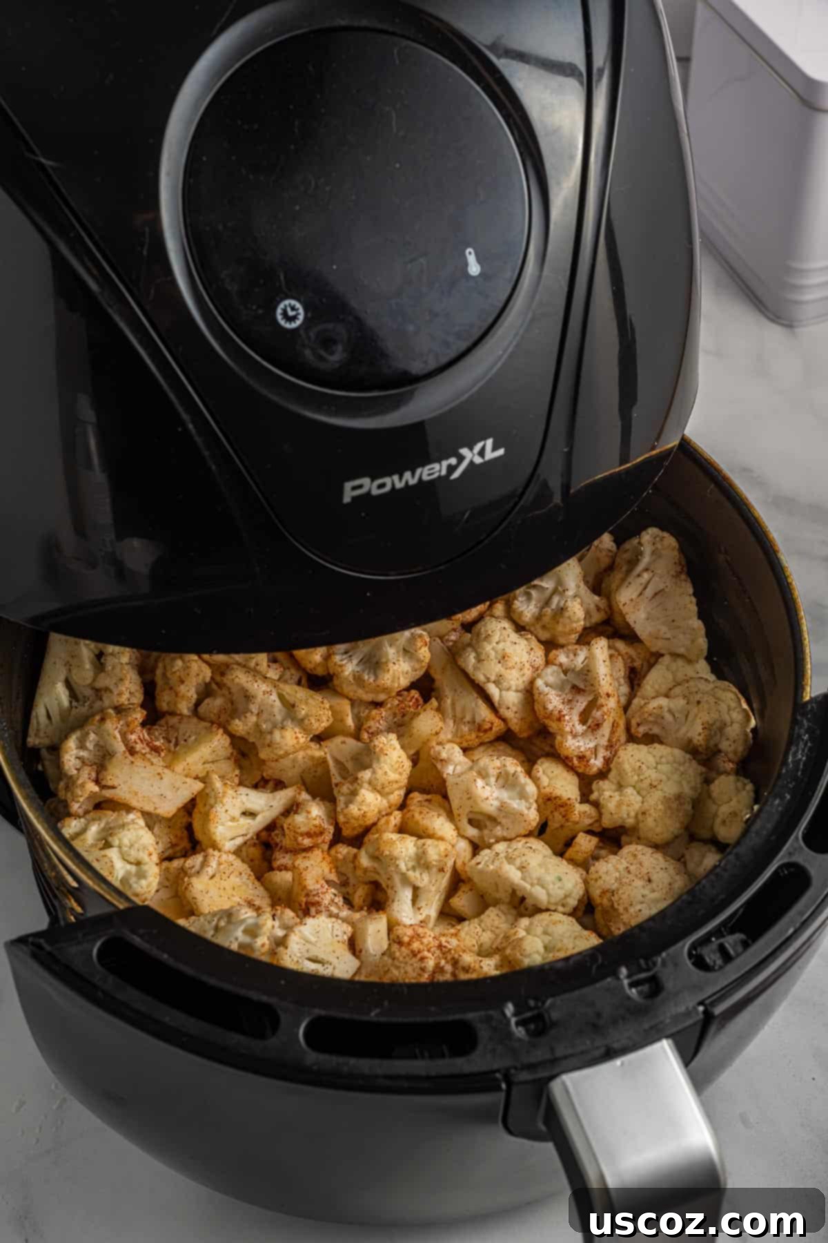 Crispy Air Fryer Cauliflower 7 Crispy golden-brown cauliflower florets cooking in an air fryer basket.