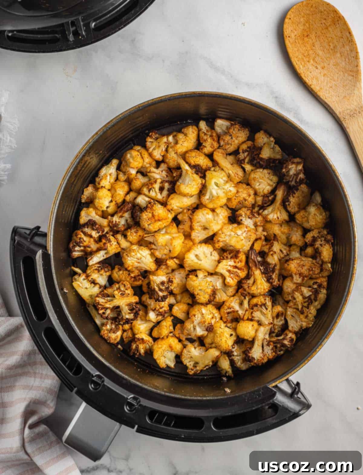Crispy Air Fryer Cauliflower 8 Delicious crispy air fried cauliflower served directly in the air fryer basket, showing its golden-brown texture.