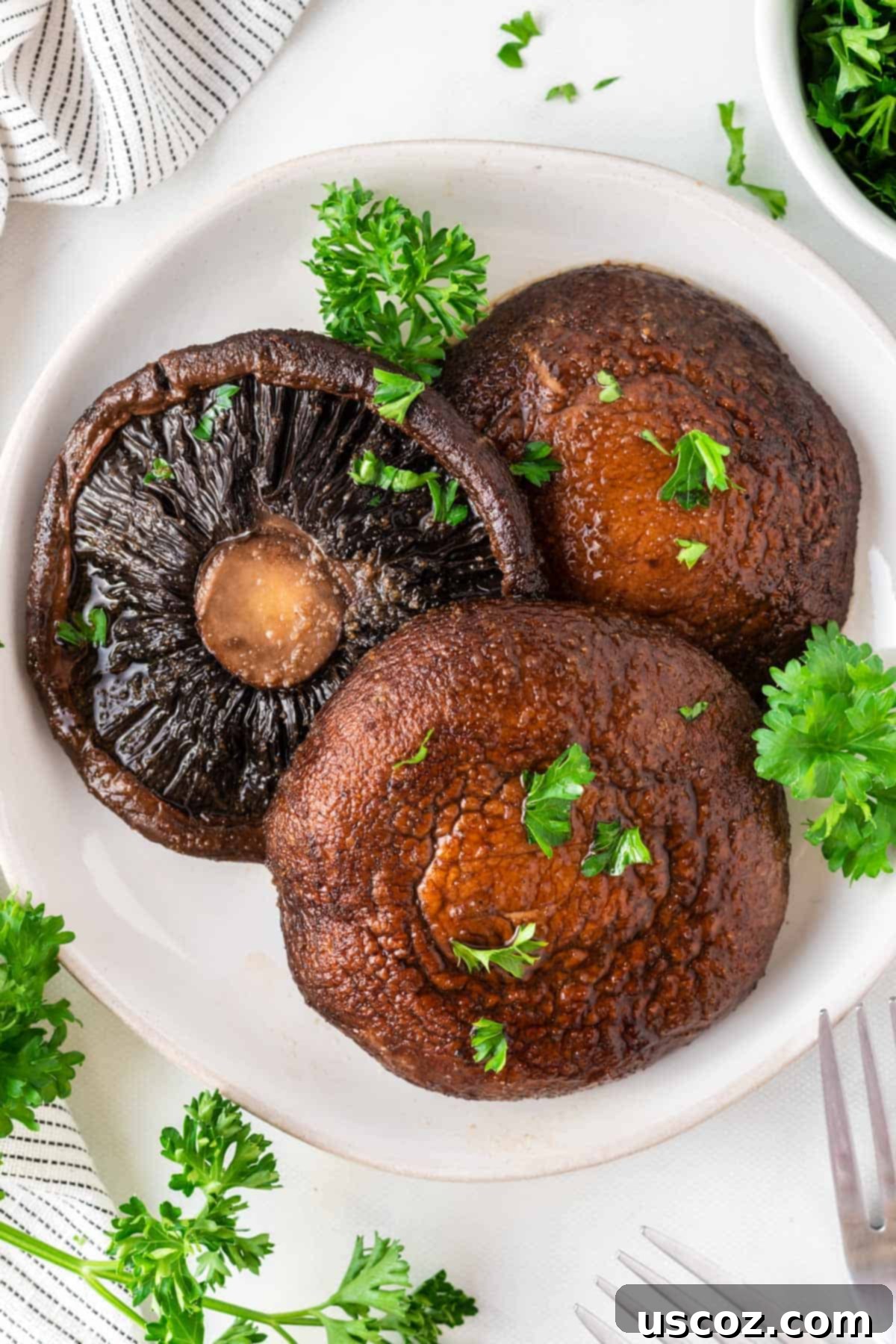 Crispy Air Fryer Portobello Mushrooms 2 portobello mushrooms topped with parsley on a plate