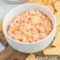 Pimento Cheese 12 Creamy homemade pimento cheese dip served with a variety of crackers on a rustic wooden board.