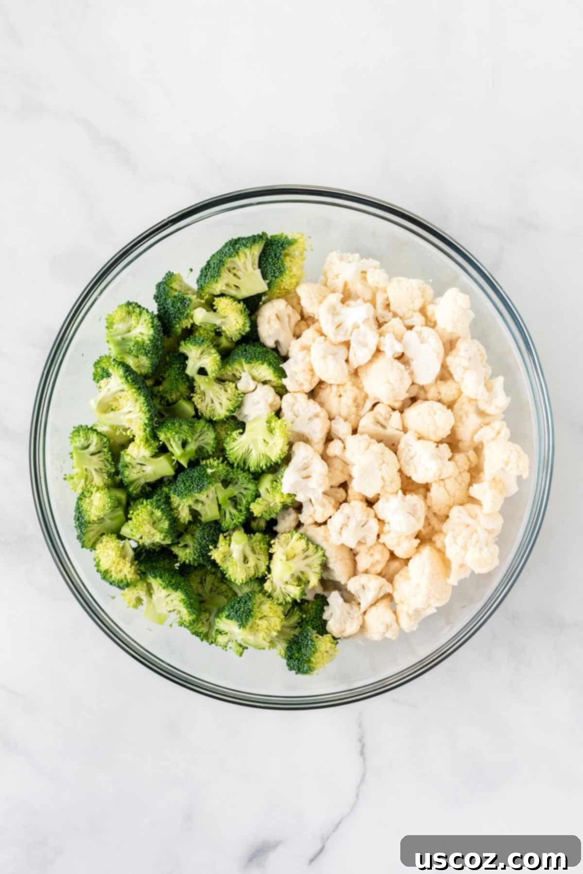 Golden Roasted Broccoli and Cauliflower 5 A clean, white bowl brimming with freshly cut and dried broccoli and cauliflower florets, glistening and ready for seasoning.