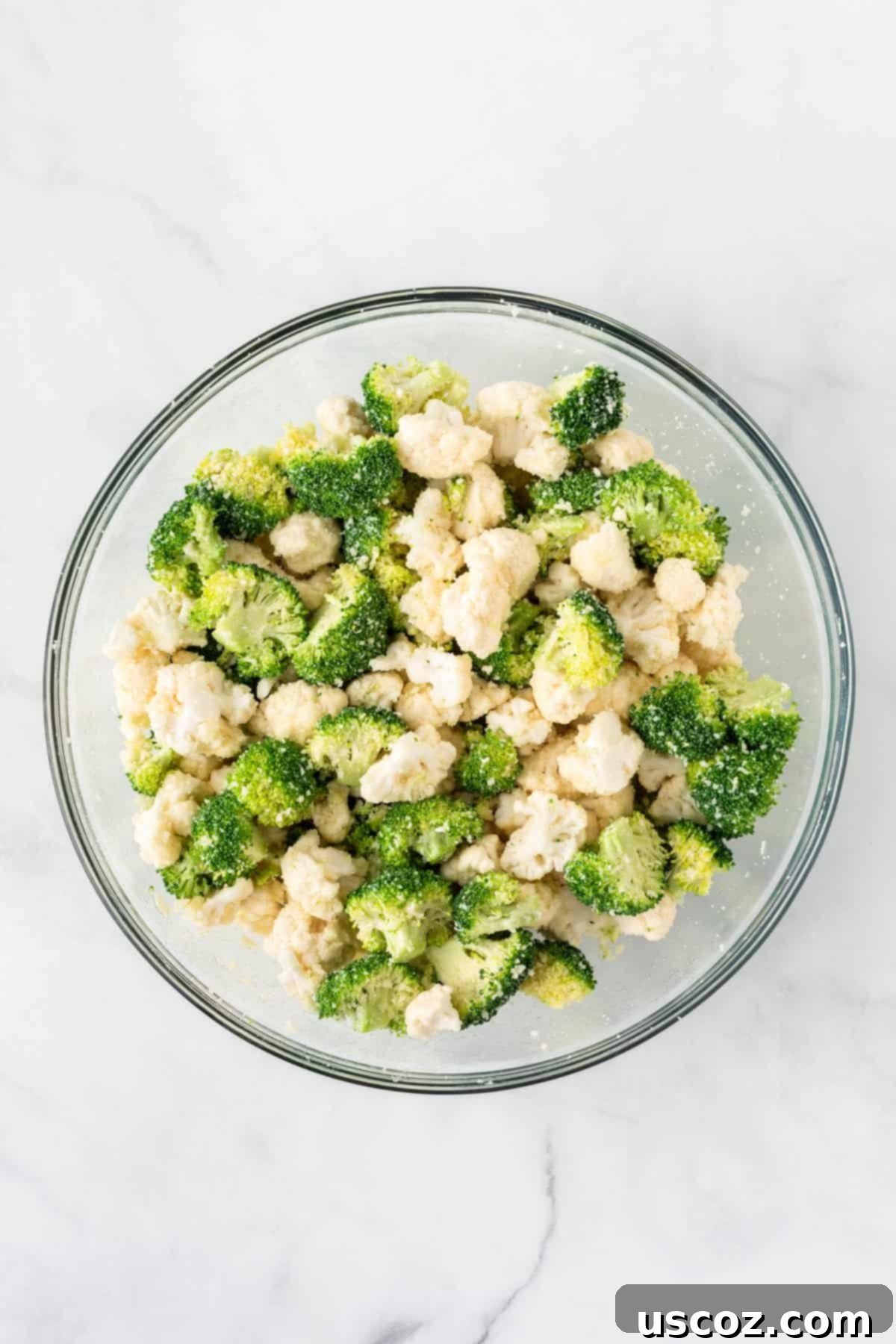 Golden Roasted Broccoli and Cauliflower 7 A close-up shot of broccoli and cauliflower florets in a bowl, perfectly seasoned and glistening with olive oil, garlic, and parmesan.