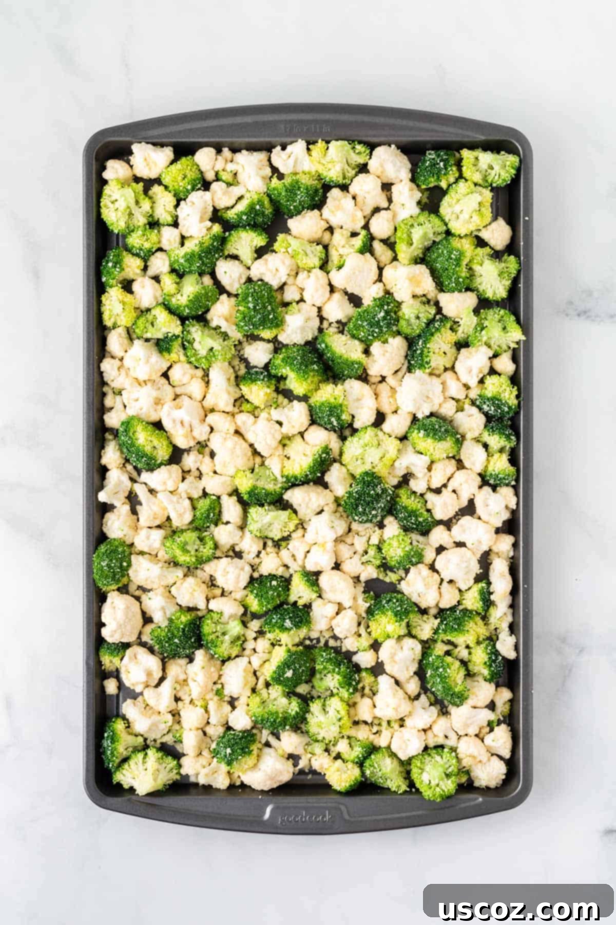 Golden Roasted Broccoli and Cauliflower 8 Seasoned broccoli and cauliflower florets being carefully arranged in a single, even layer on a nonstick baking sheet, ready to go into the oven for roasting.