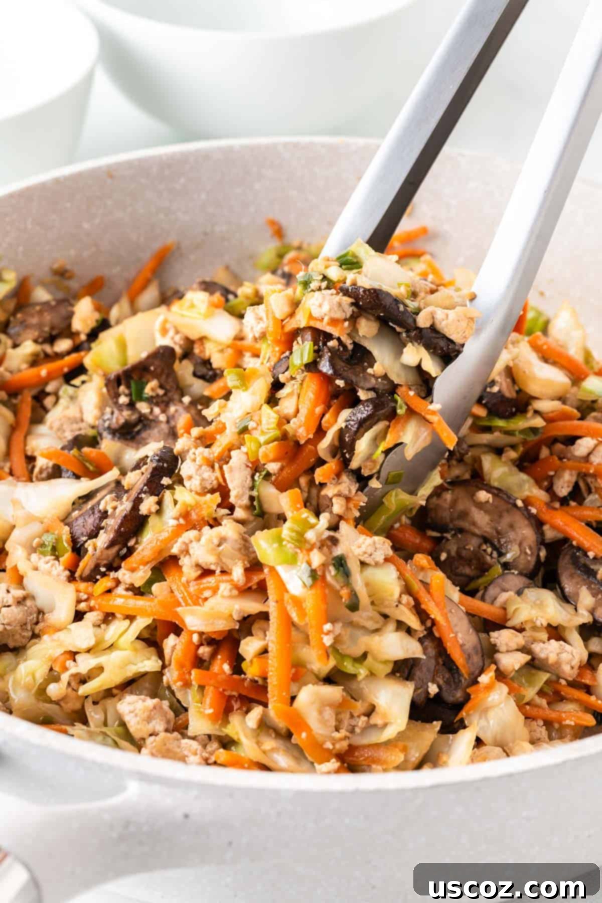 Easy Vegetarian Egg Roll Bowl 2 tongs taking egg roll filling from the skillet