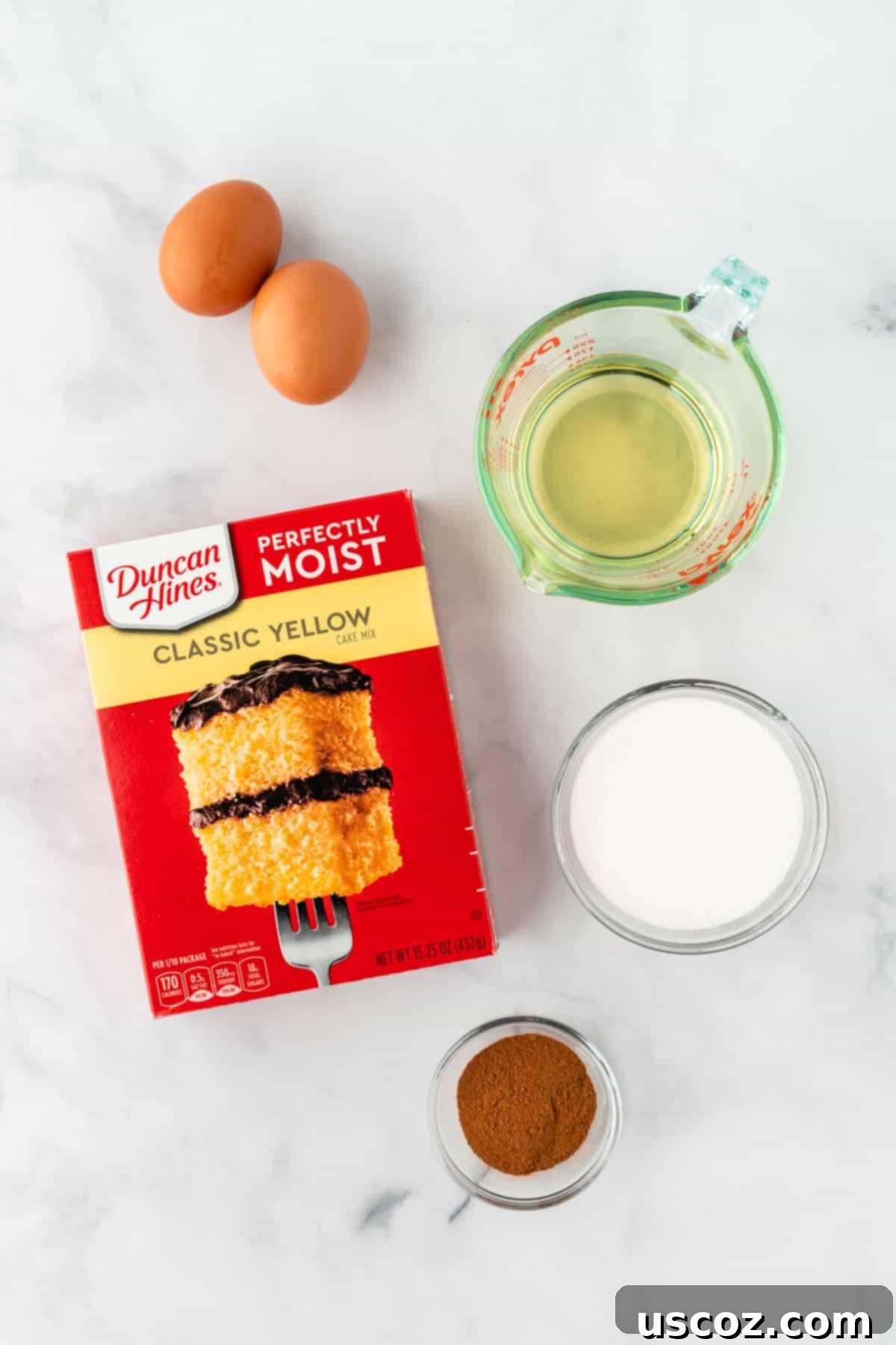 Effortless Cake Mix Snickerdoodles 4 All ingredients for cake mix snickerdoodles laid out: yellow cake mix box, olive oil, eggs, cinnamon, and sugar