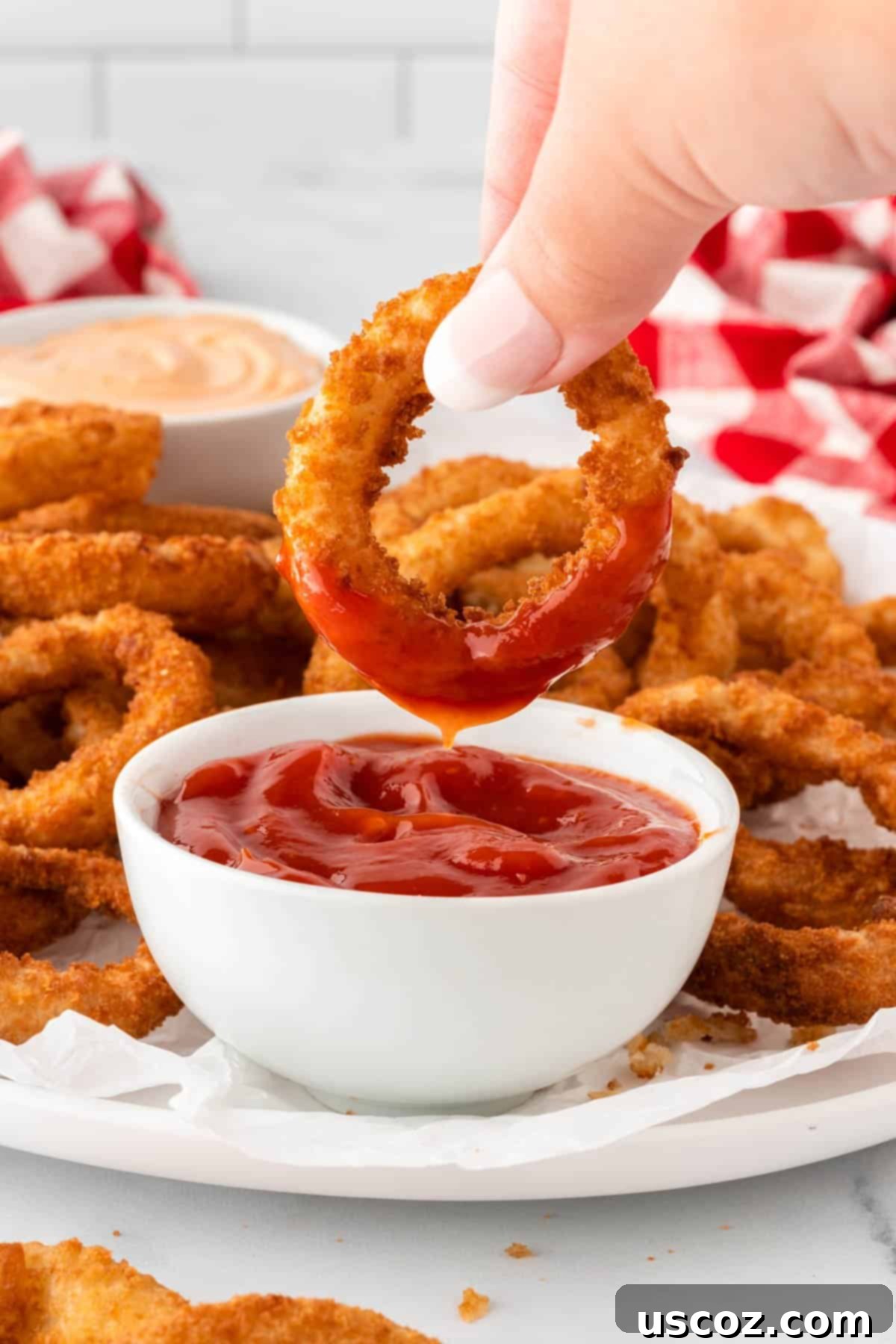 Crispy Air Fryer Frozen Onion Rings 3 dipping an onion ring into ketchup
