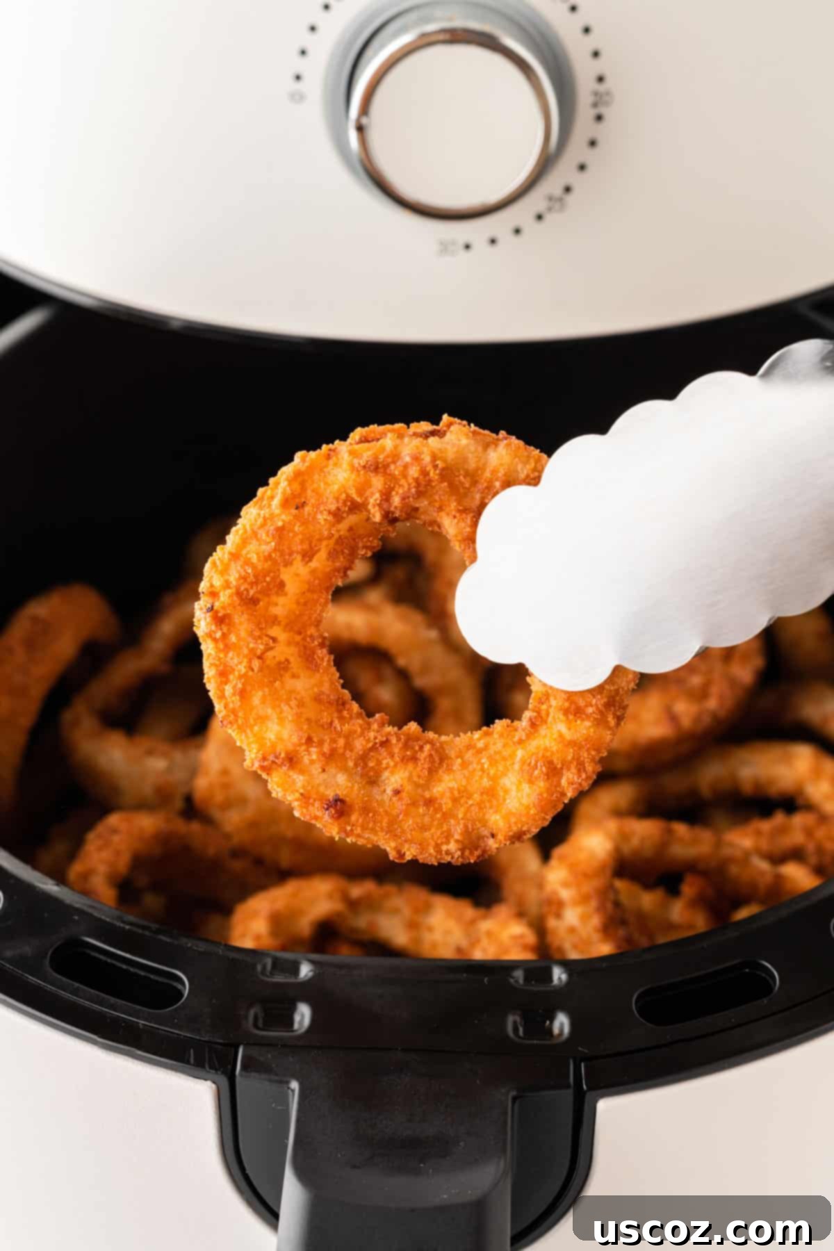 Crispy Air Fryer Frozen Onion Rings 6 taking an onion ring from the air fryer