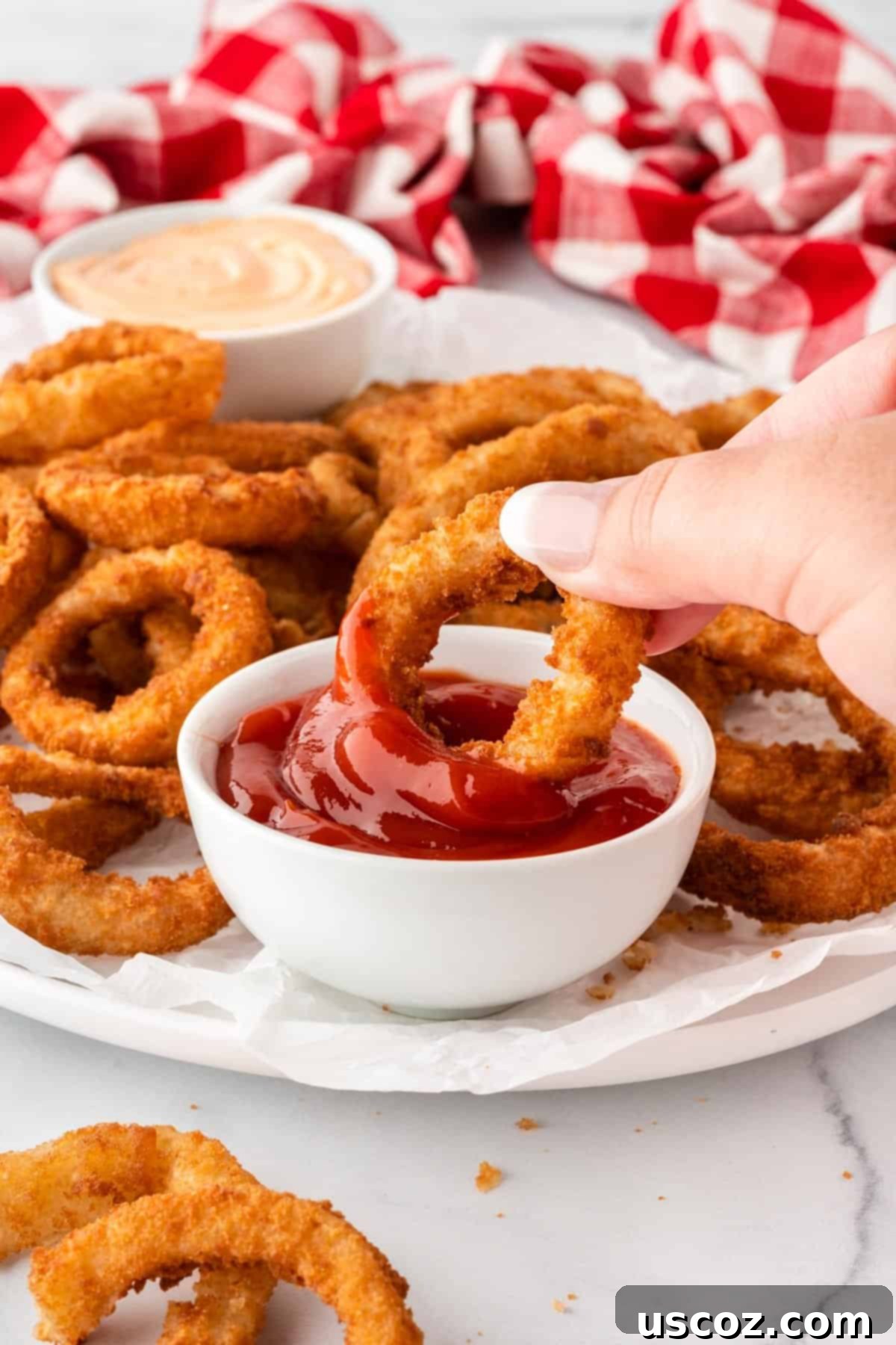 Crispy Air Fryer Frozen Onion Rings 8 dipping an onion ring into ketchup