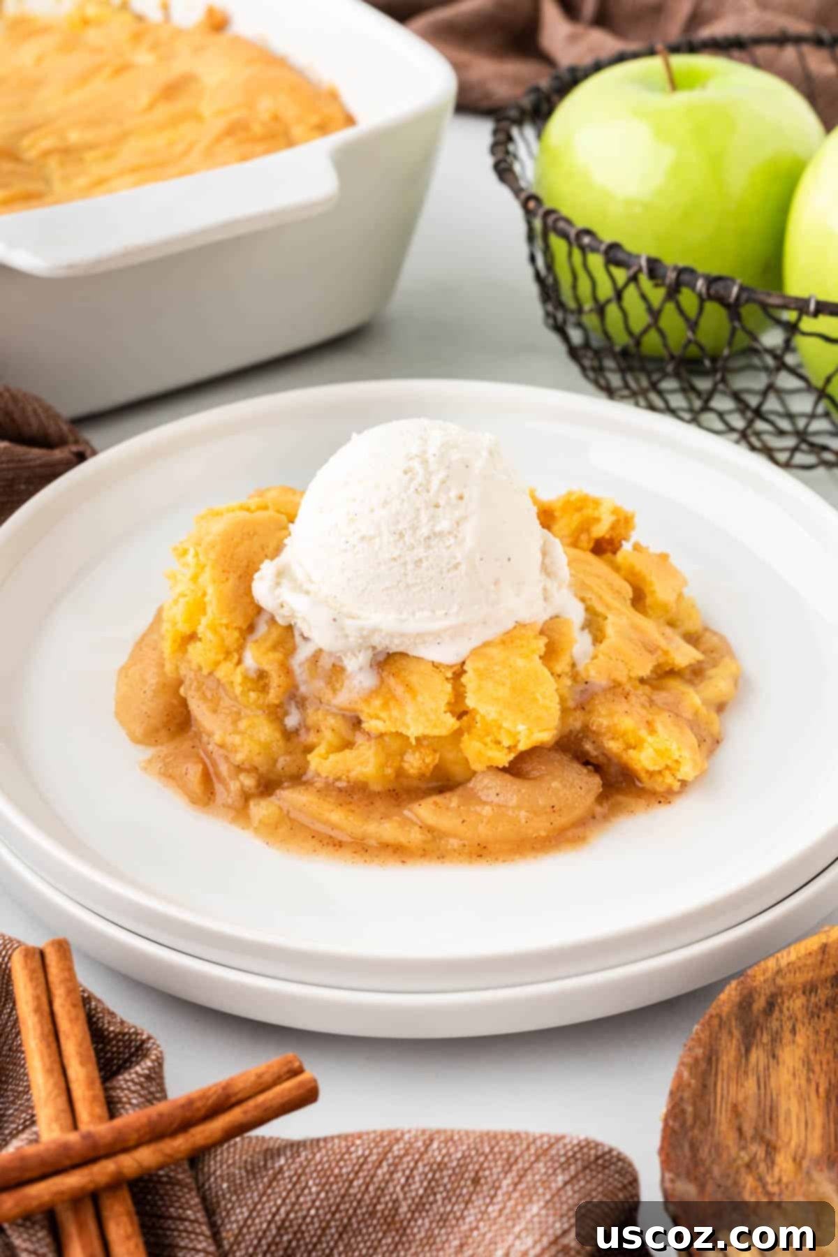 Effortless Apple Cobbler 2 A serving of warm cake mix apple cobbler topped with a scoop of vanilla ice cream, on a white plate