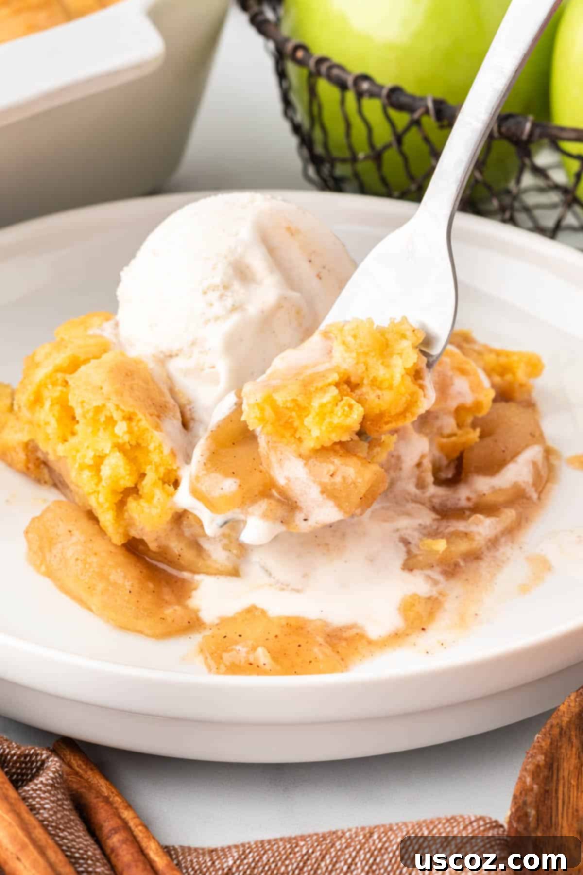 Effortless Apple Cobbler 14 A fork taking a bite of the cake mix apple cobbler, showing the soft topping and the flavorful apple filling.