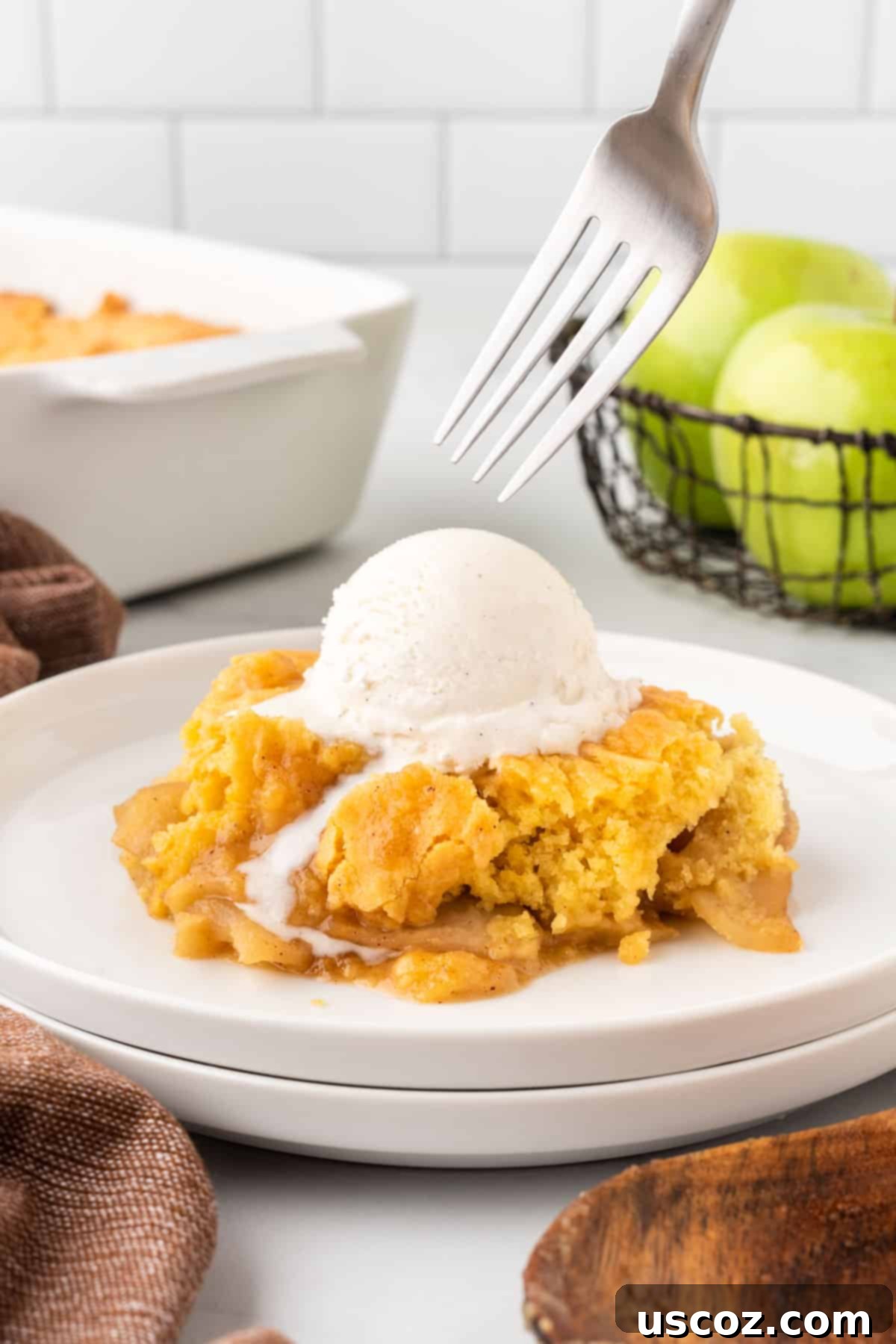 Effortless Apple Cobbler 15 A slice of apple cobbler with vanilla ice cream and a spoon on a white plate, highlighting the deliciousness of this easy dessert.