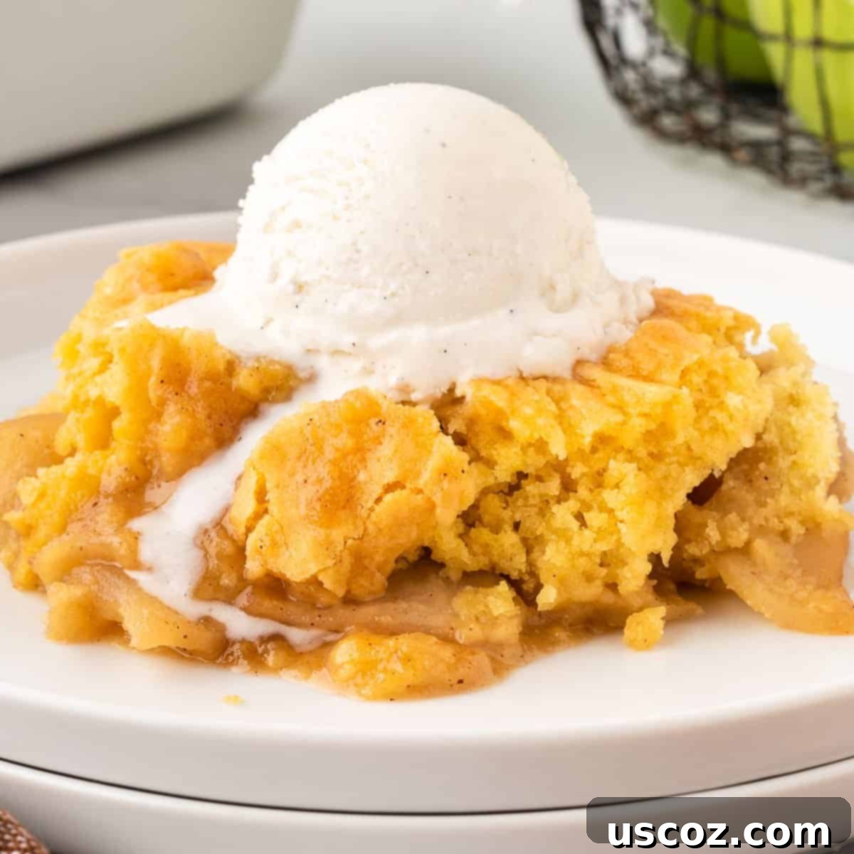 Effortless Apple Cobbler 16 A top-down view of a serving of cake mix apple cobbler with a scoop of ice cream on top, ready to be enjoyed.