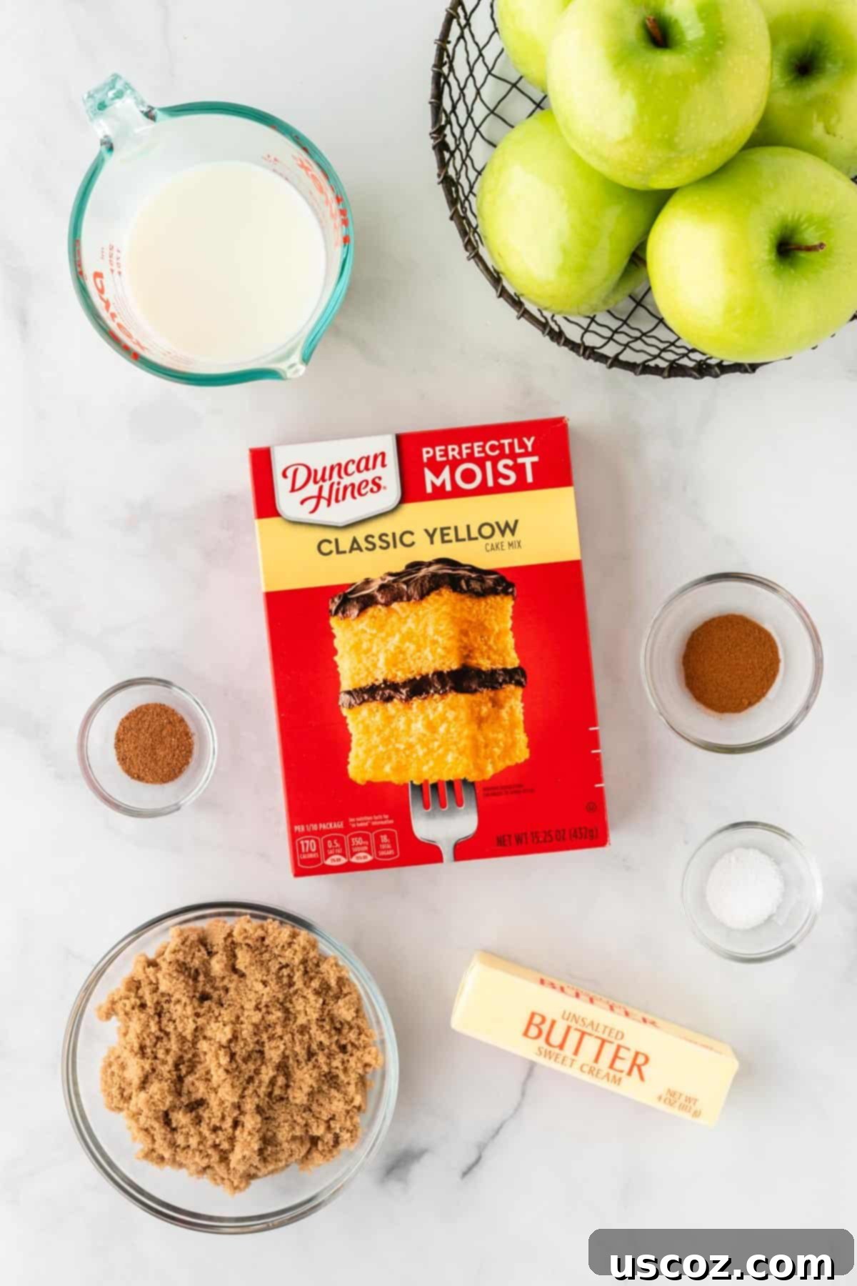 Effortless Apple Cobbler 3 All the ingredients neatly laid out for making a cake mix apple cobbler: Granny Smith apples, brown sugar, spices, yellow cake mix, butter, and milk