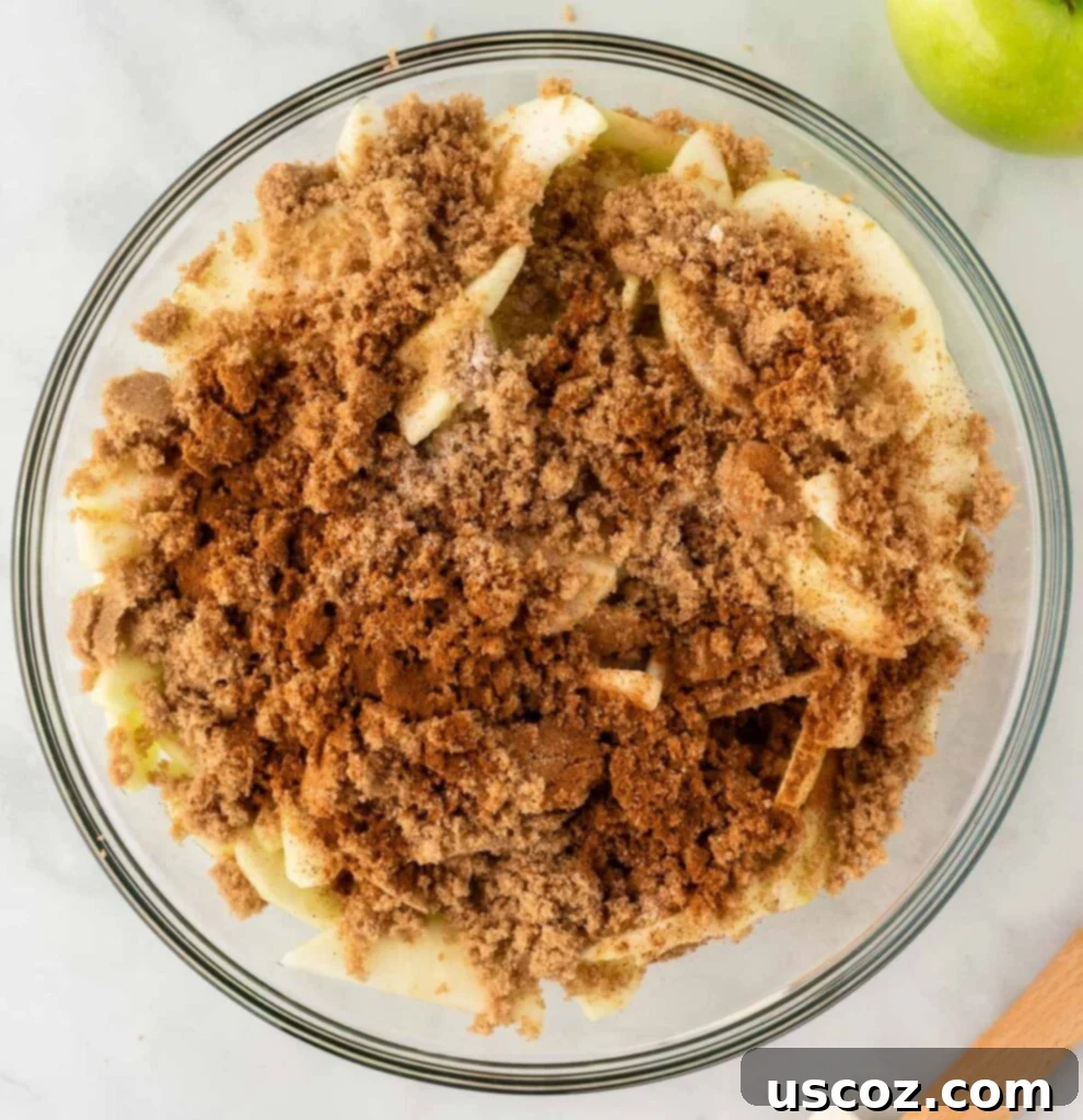 Effortless Apple Cobbler 5 Sliced apples in a bowl, generously sprinkled with brown sugar, cinnamon, and nutmeg.