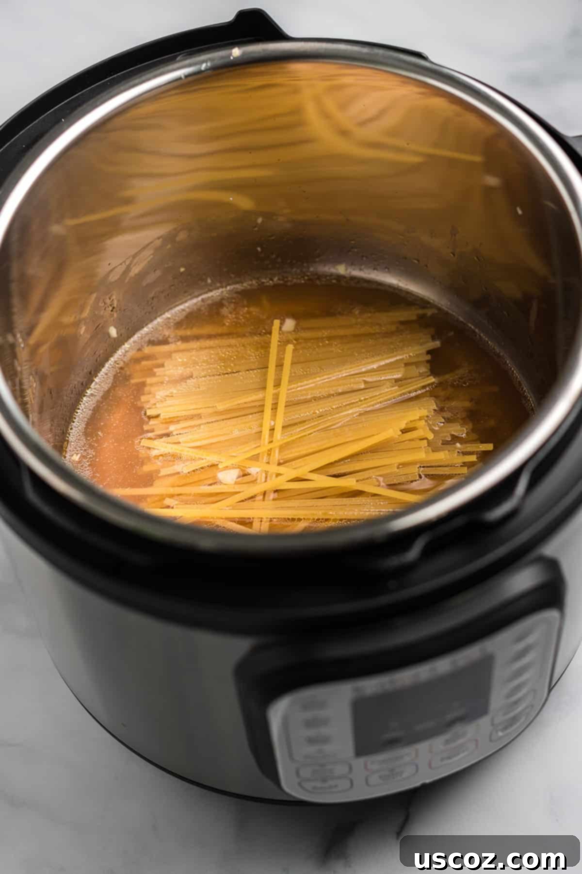 Quick and Creamy Instant Pot Pasta 5 Linguine noodles being added to vegetable broth in the Instant Pot, ensuring they are fully submerged.