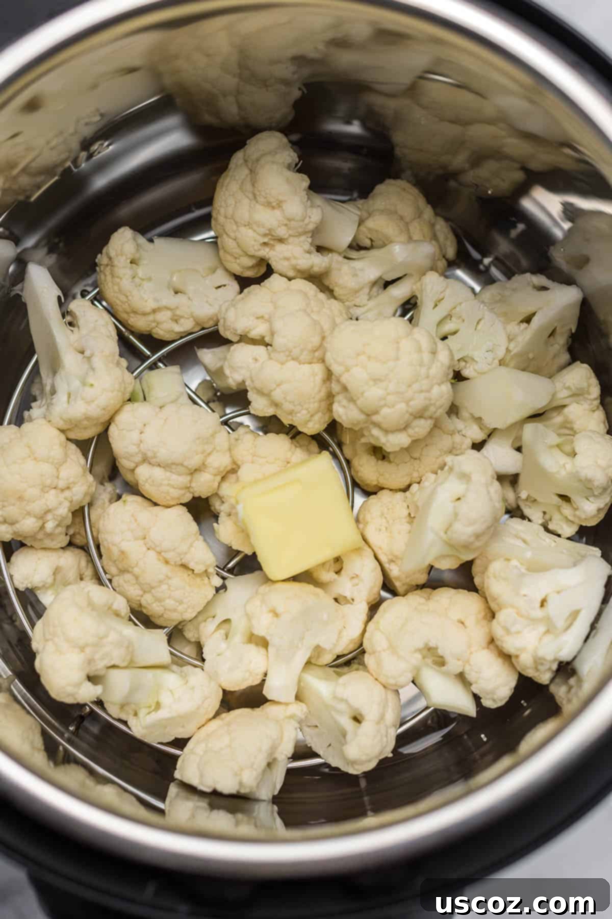 Easy Instant Pot Cauliflower 5 cauliflower florets inside an instant pot with a pat of butter on top