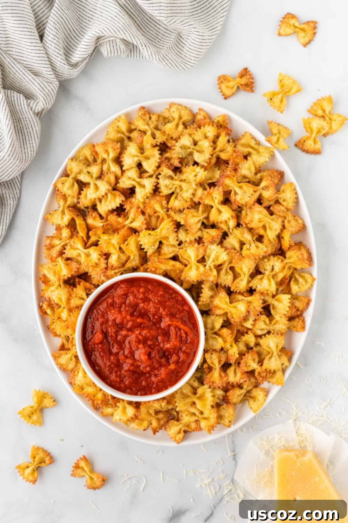 Crispy Air Fryer Pasta Chips 12 Air fried pasta chips arranged on a plate with a bowl of marinara, ready to be served as a delightful appetizer.