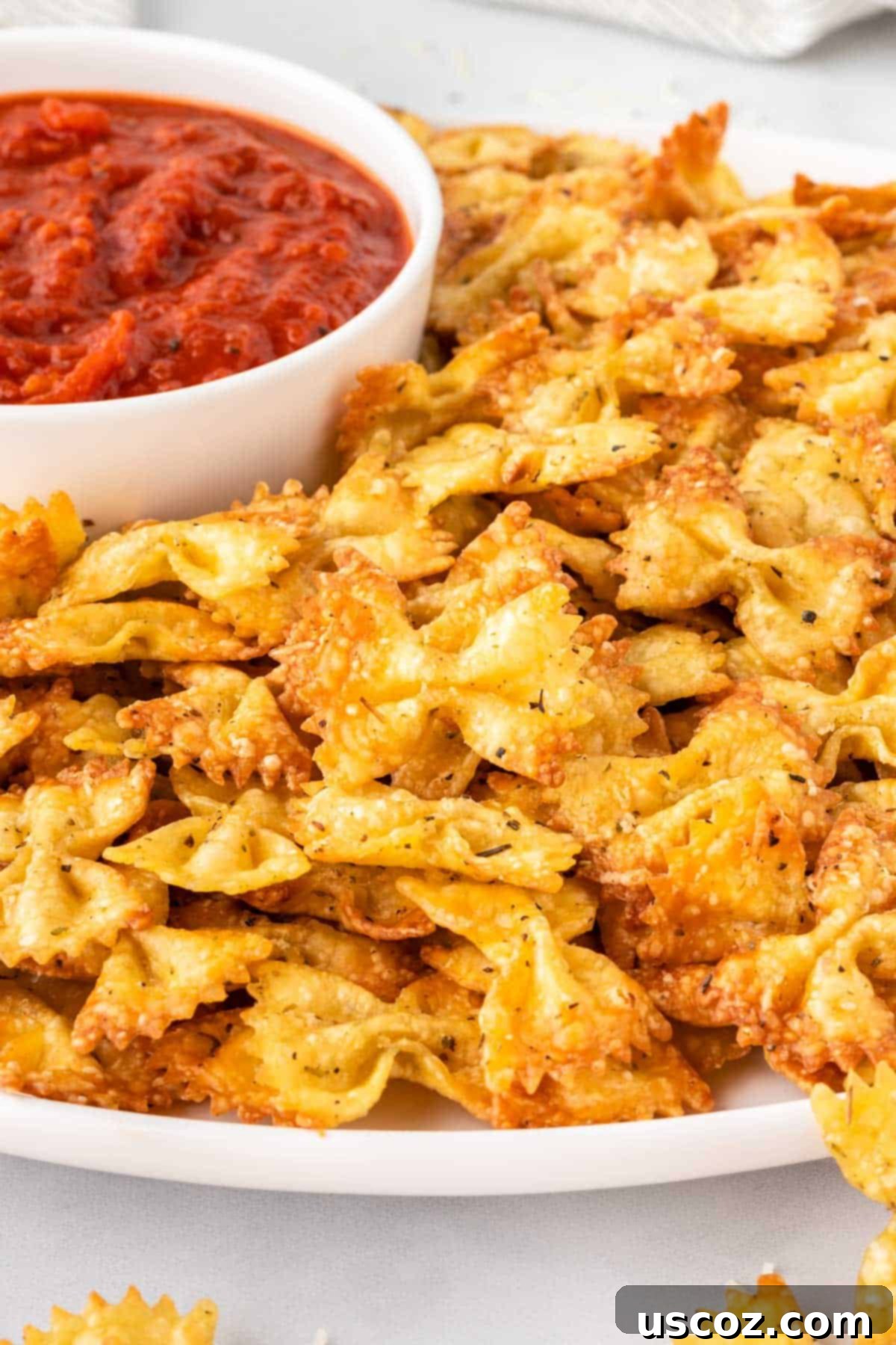 Crispy Air Fryer Pasta Chips 15 A beautifully plated serving of air fryer pasta chips with a ramekin of marinara sauce for dipping.