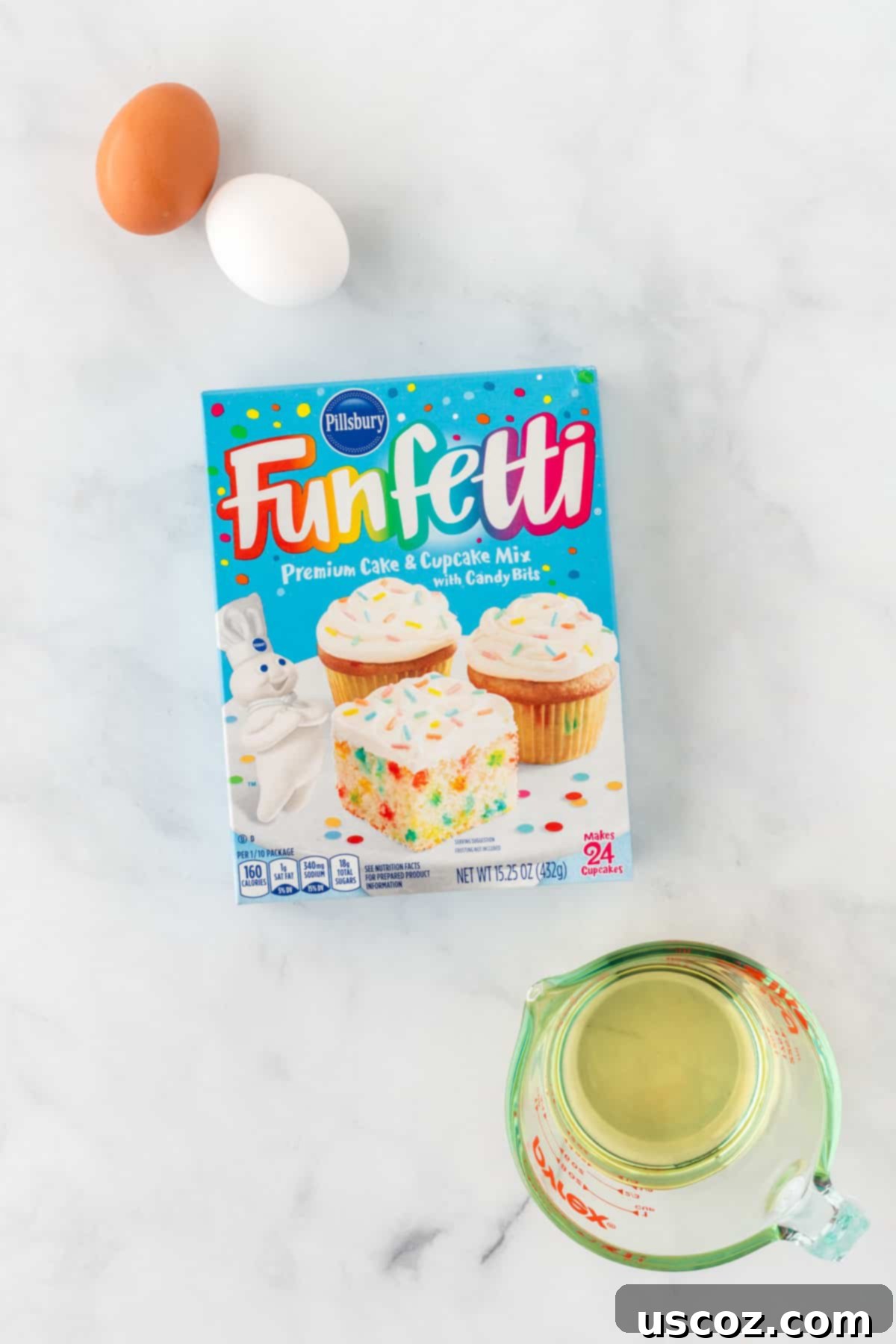 Effortless Rainbow Cake Cookies 4 Three key ingredients for funfetti cookies: a box of funfetti cake mix, eggs, and a bottle of olive oil, neatly arranged for baking.