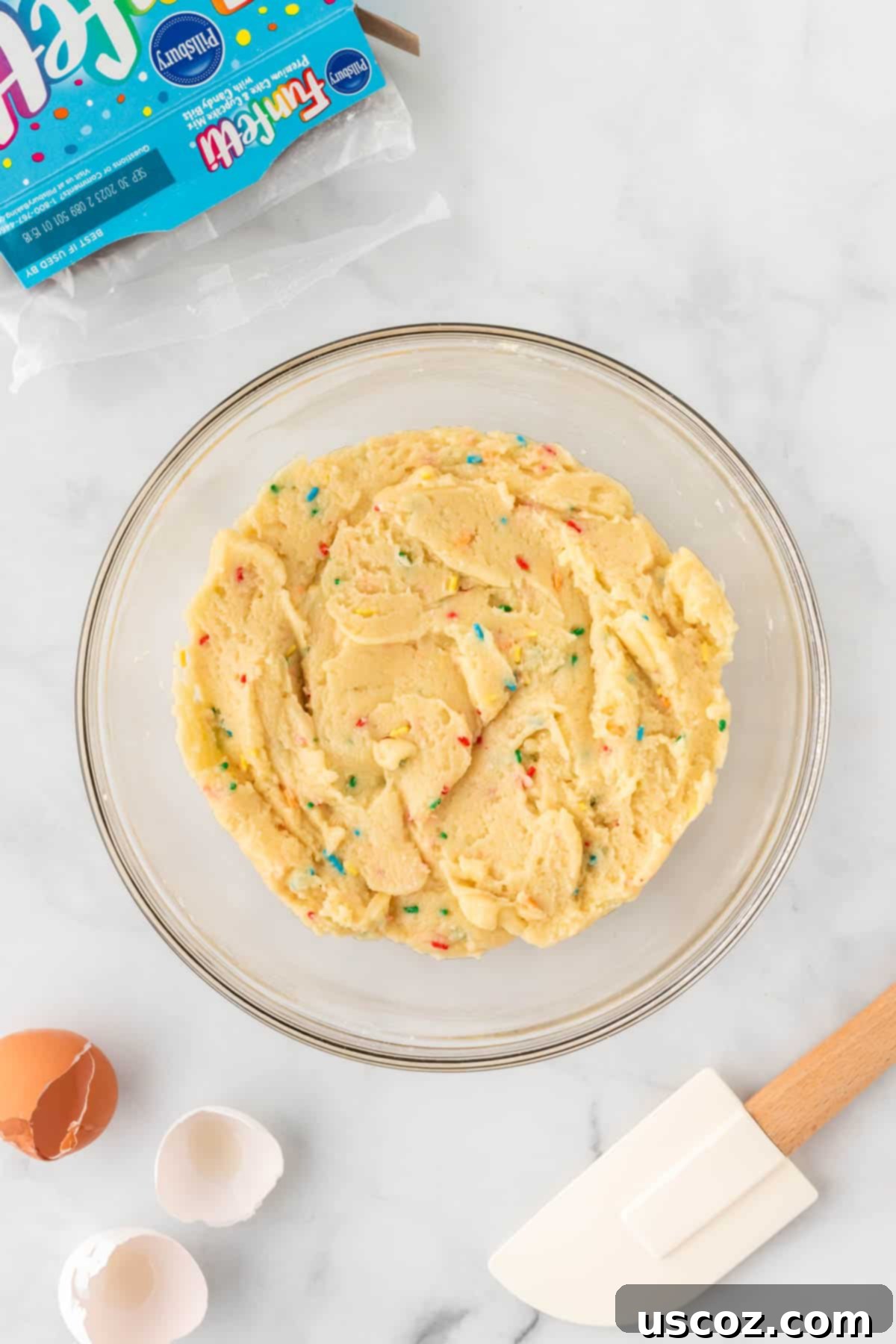 Effortless Rainbow Cake Cookies 7 A close-up of the funfetti cake mix cookie batter in a bowl, showcasing its vibrant sprinkles and smooth texture.