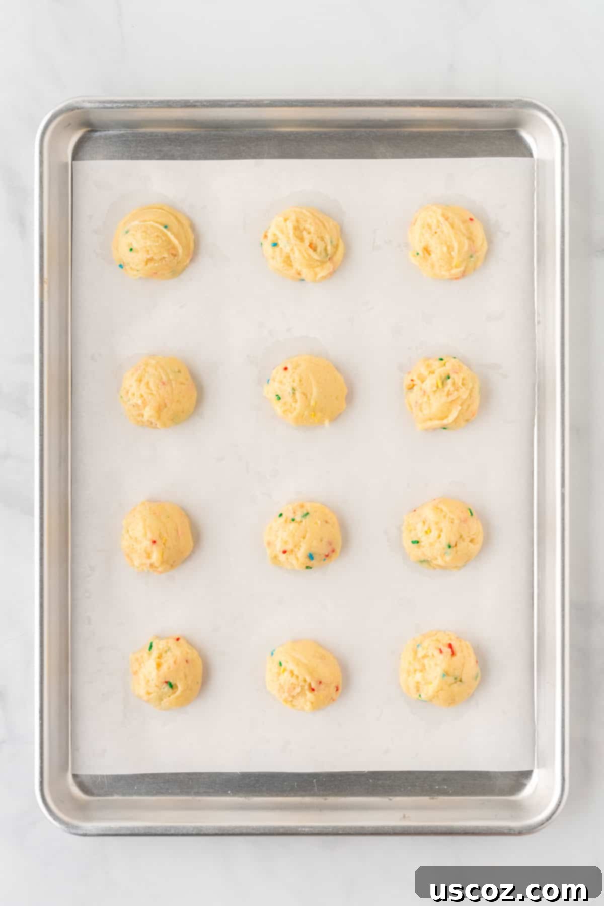 Effortless Rainbow Cake Cookies 8 Neatly portioned cookie dough balls arranged on a baking sheet, ready for the oven, demonstrating proper spacing.