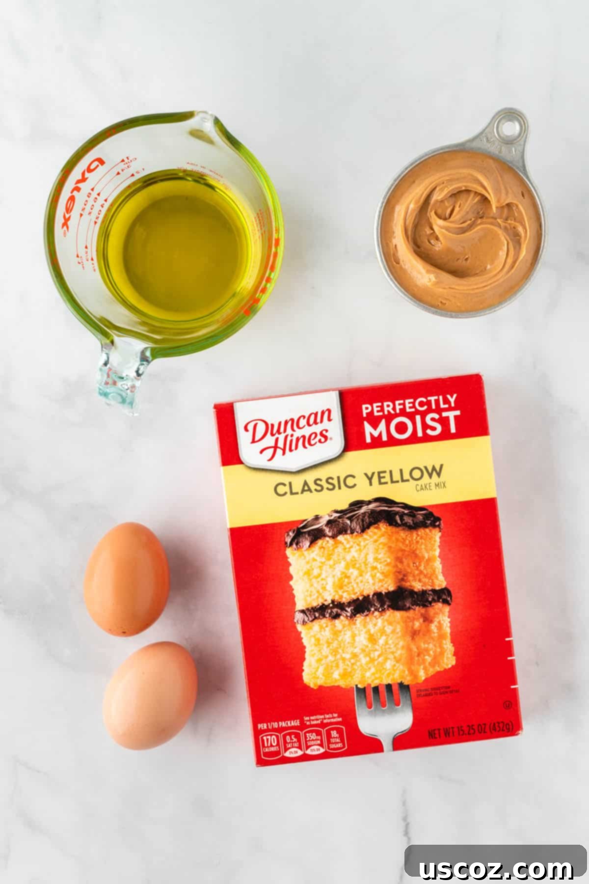 Easy Cake Mix Peanut Butter Cookies 4 All four ingredients neatly laid out on a kitchen counter: a box of yellow cake mix, creamy peanut butter, eggs, and olive oil.