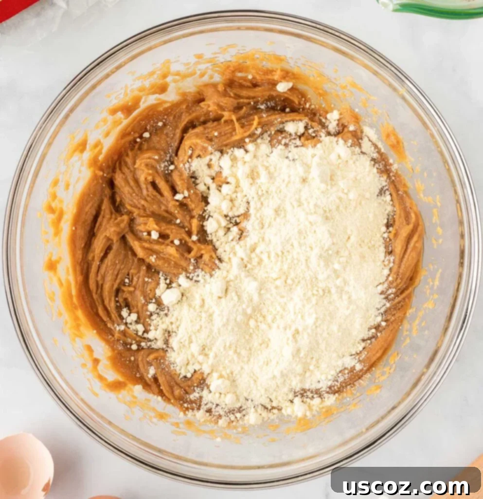 Easy Cake Mix Peanut Butter Cookies 7 Pouring the yellow cake mix into the bowl with the peanut butter, egg, and oil mixture.