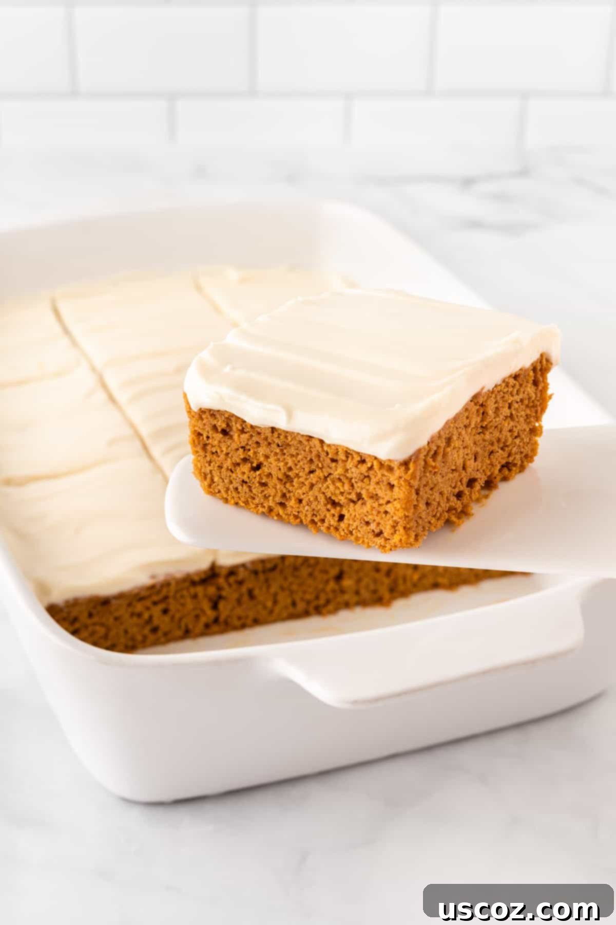 Easy Cake Mix Pumpkin Bars 2 taking a pumpkin bar from the pan, showcasing a delicious autumn treat