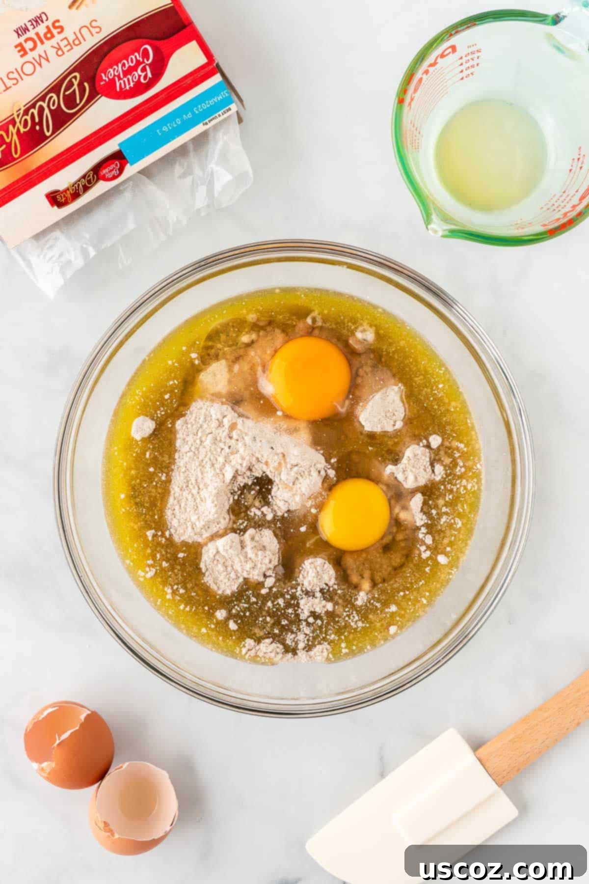 Quick Cake Mix Spice Cookies 6 Eggs and oil being added to the dry cake mix in a bowl, starting the mixing process.