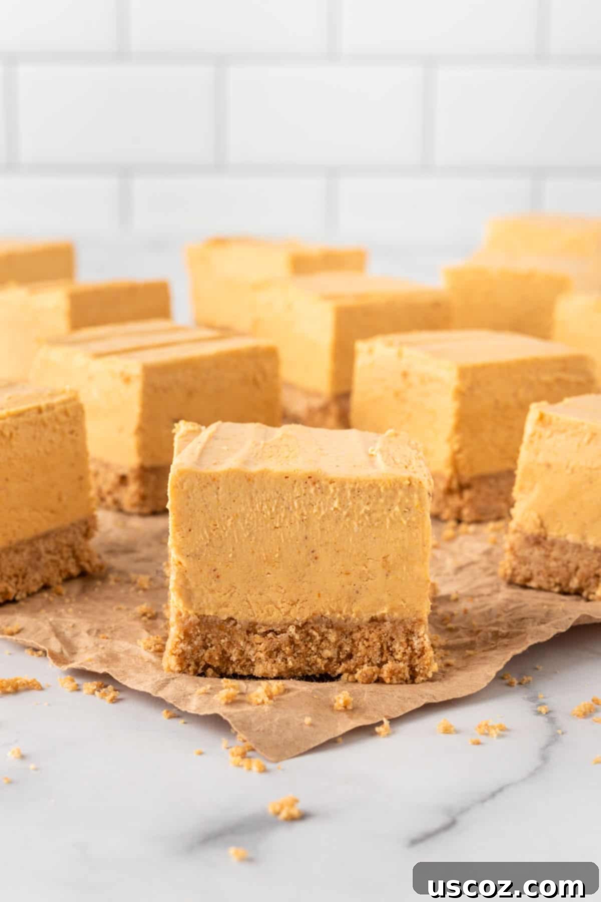 Easy No-Bake Pumpkin Cheesecake Bars 19 stacked squares of no bake pumpkin cheesecake bars on a plate