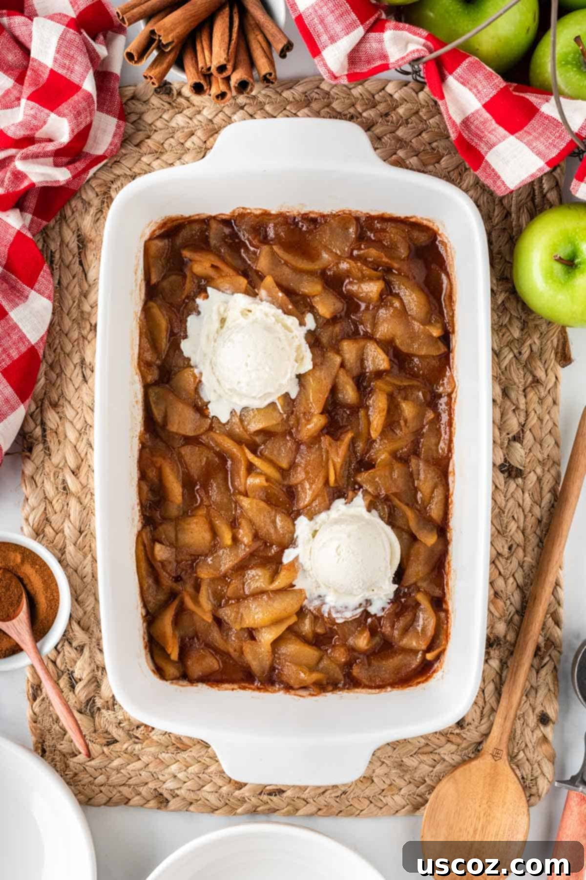 Warm Baked Cinnamon Apples 13 A wide shot of a baking dish filled with golden-brown baked cinnamon apples, generously topped with scoops of vanilla ice cream, ready to serve.